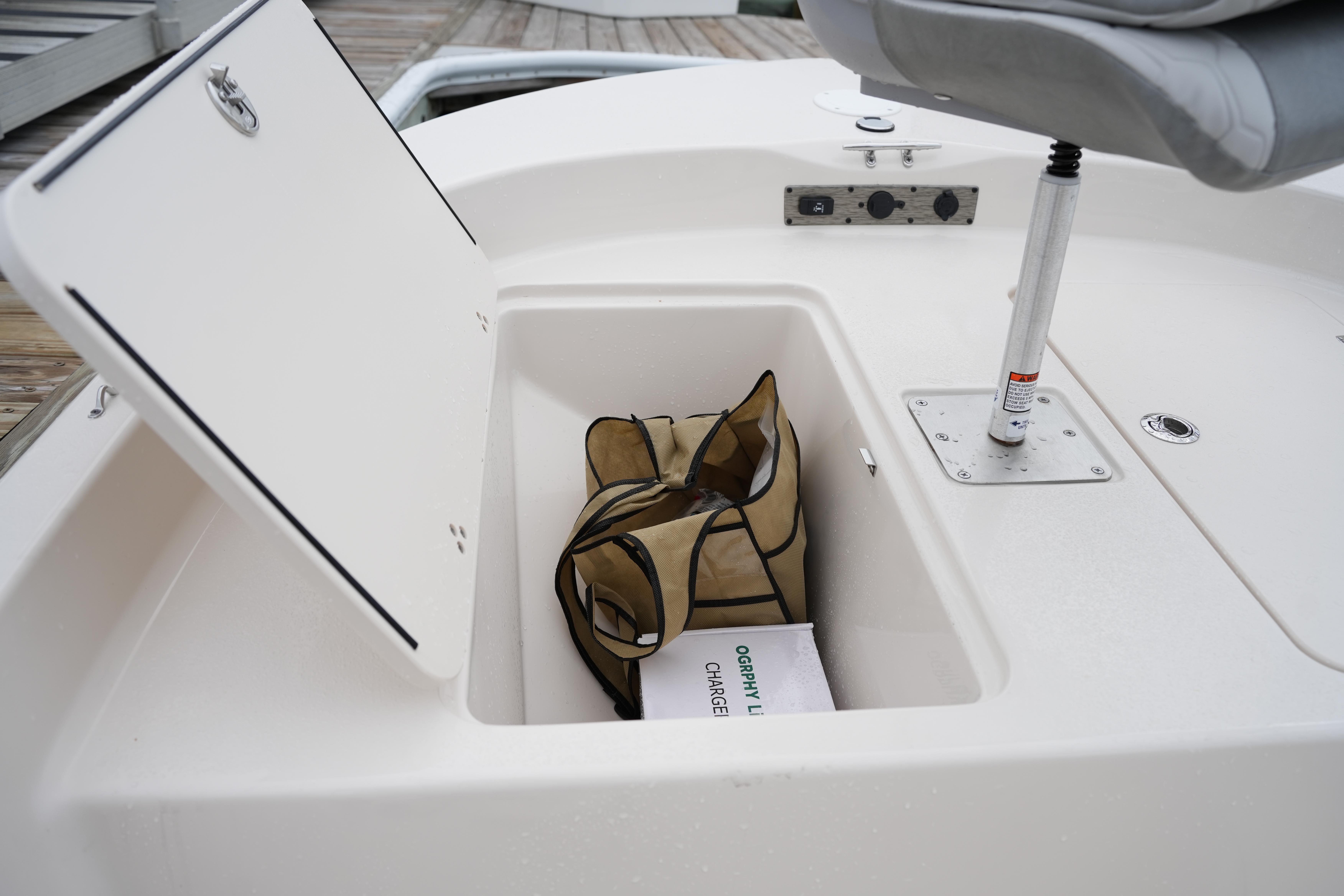 Storage compartment of 2025 Carolina Skiff 162 JLS boat with bag and charger inside.