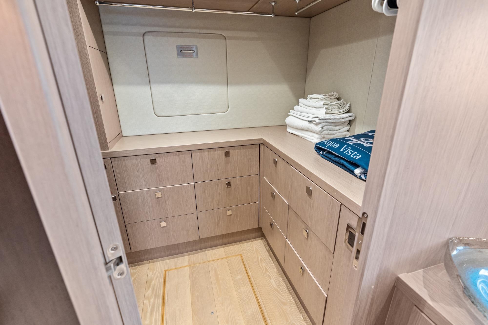 Luxurious storage area on 2019 Sunseeker 86 Yacht with wooden cabinetry and neatly stacked towels.