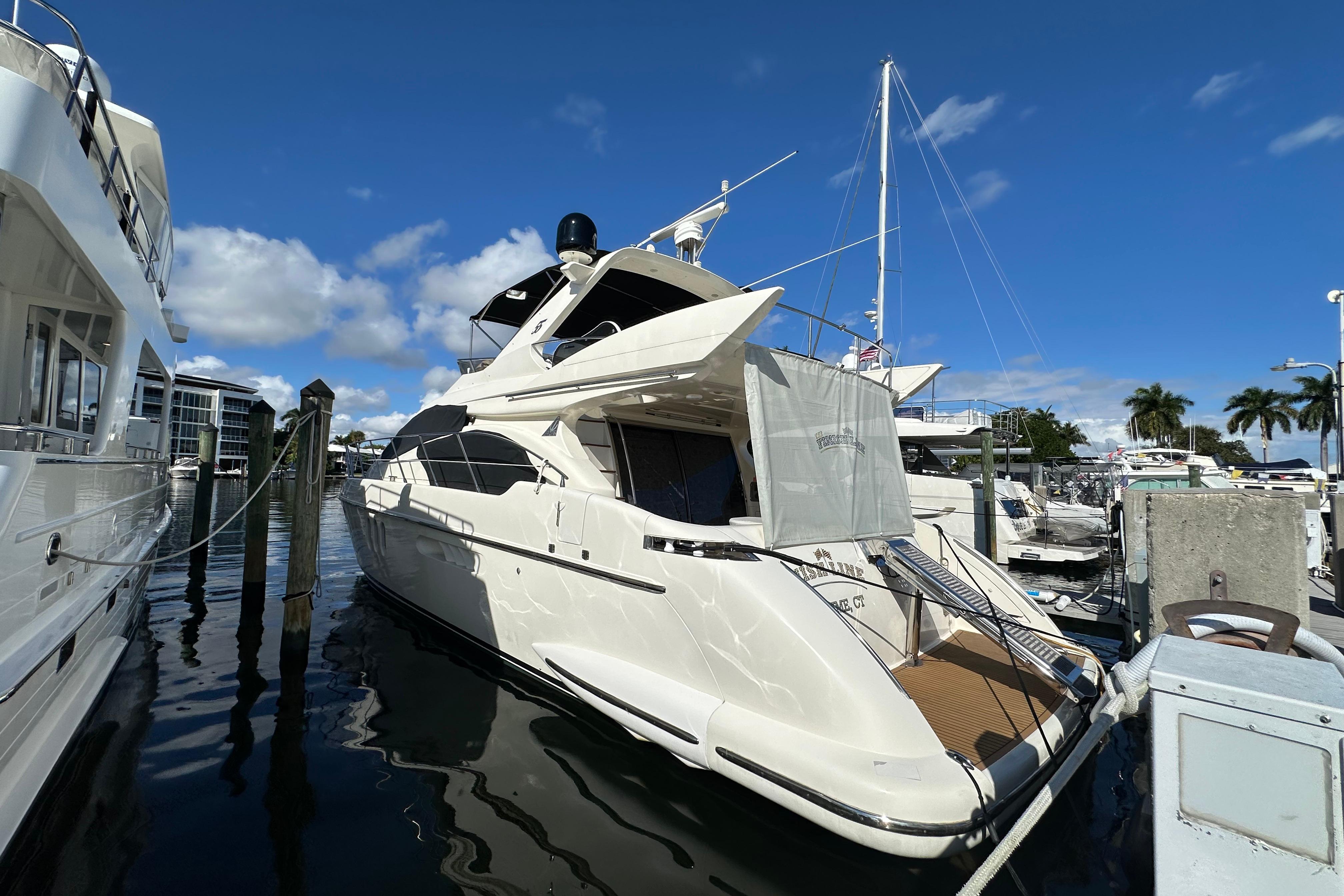 2004 Azimut 55E yacht docked at marina under clear blue sky.
