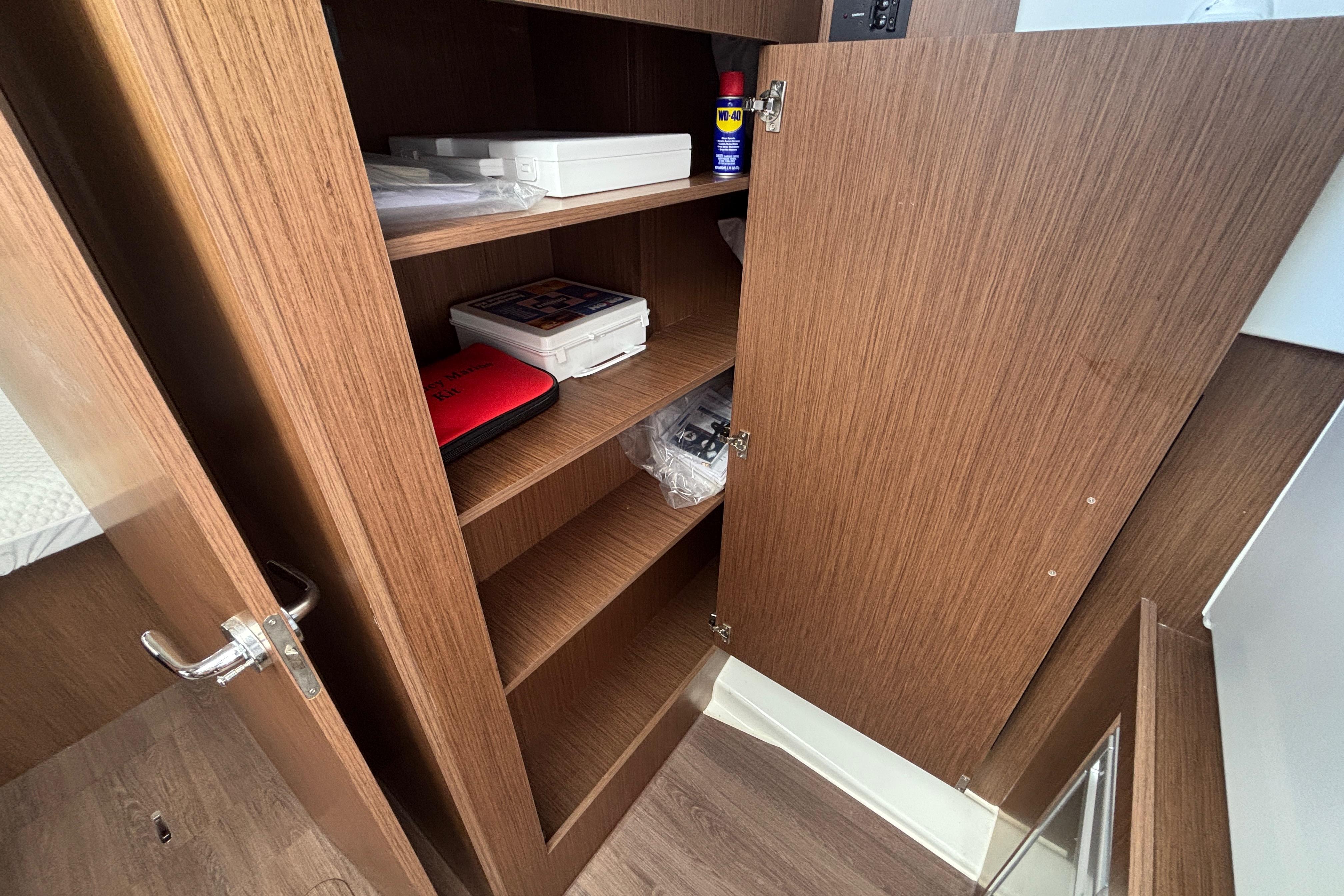 Wooden storage cabinet inside 2024 Beneteau Antares 11 boat, featuring shelves with various items.