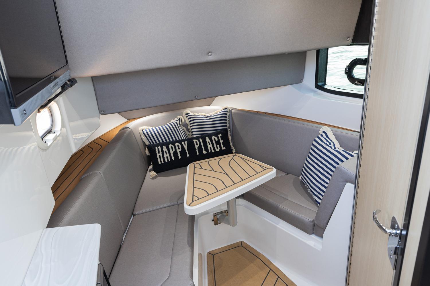 2026 Hurricane SunDeck 3200 OB cabin interior with cozy seating and nautical decor.