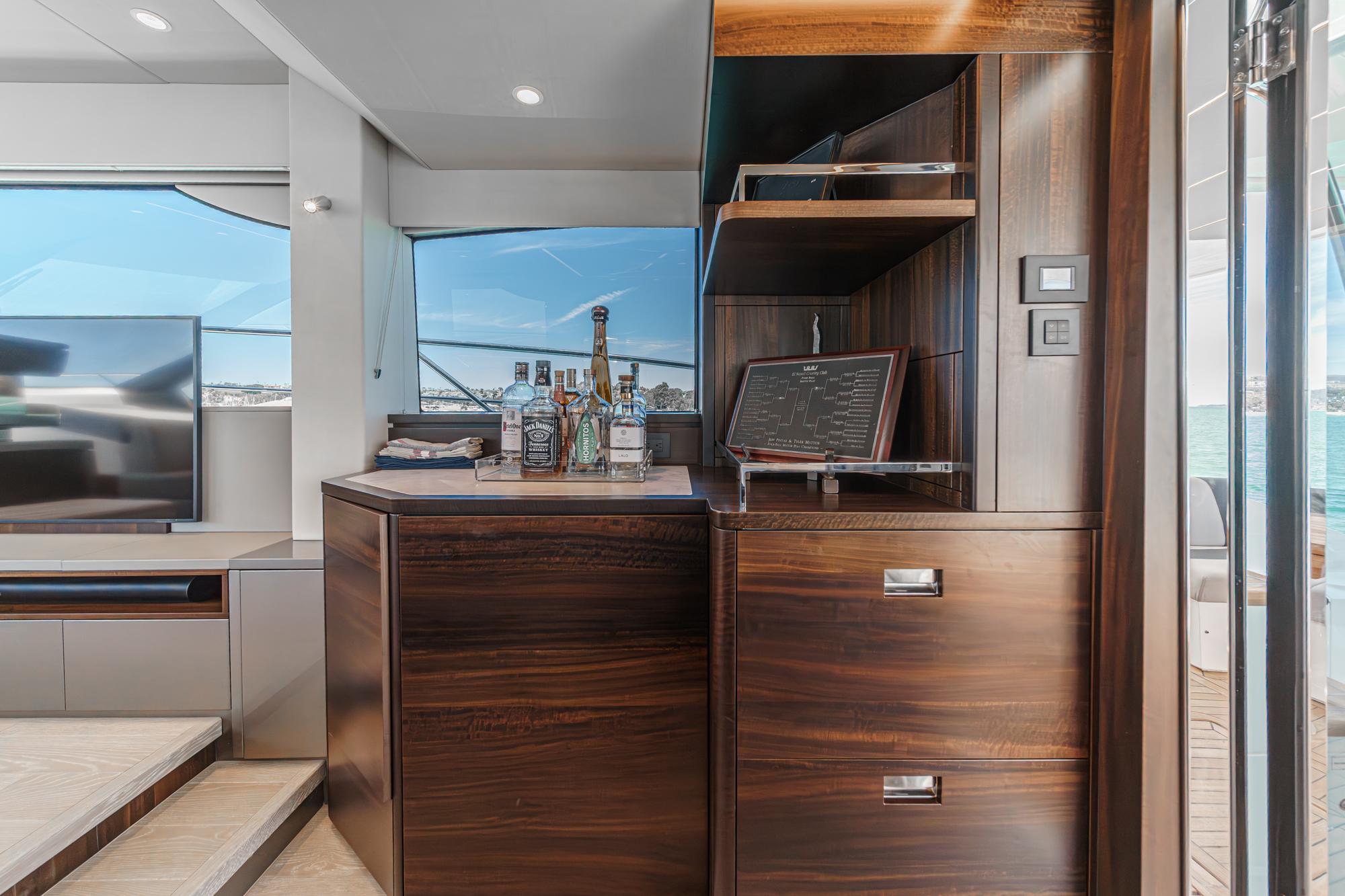 Luxurious interior of 2022 Sunseeker Manhattan 55 yacht with elegant wood cabinetry and bar setup.
