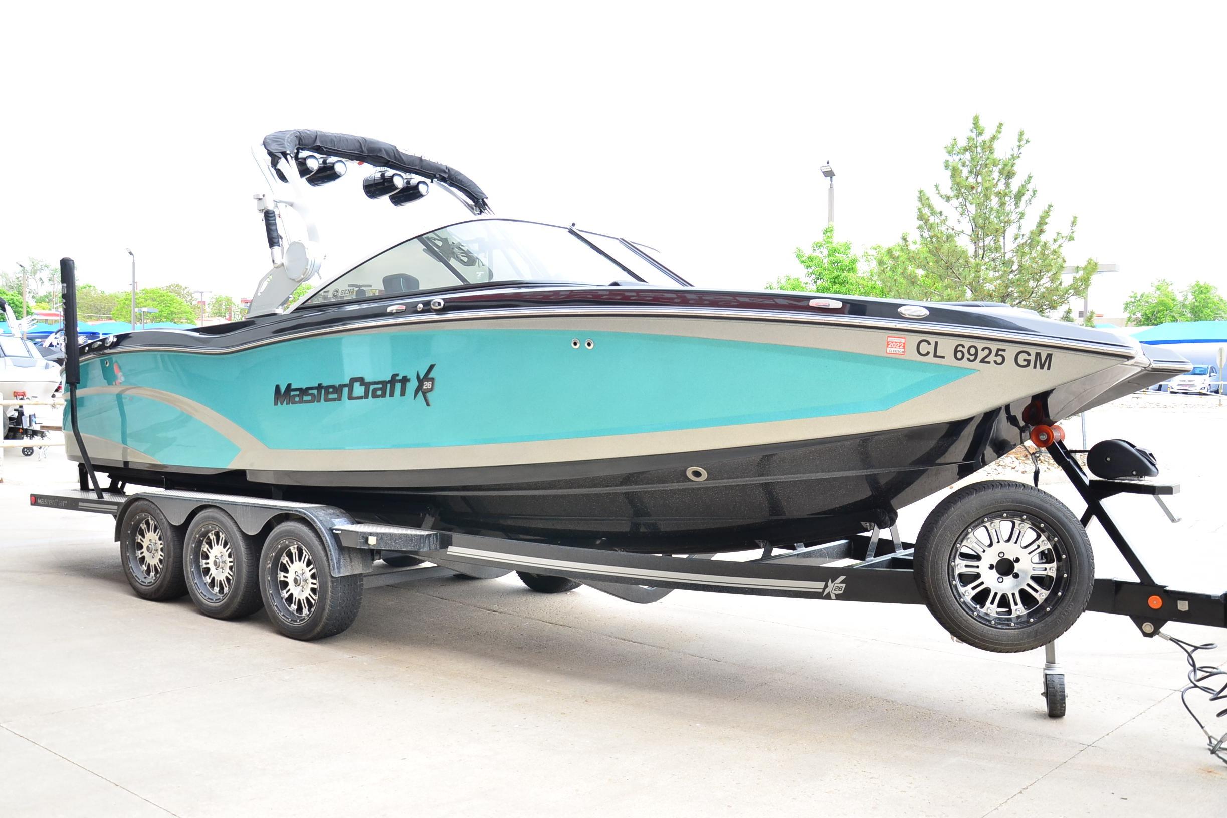 2017 MasterCraft X26 boat on trailer, turquoise and black design, parked outdoors.