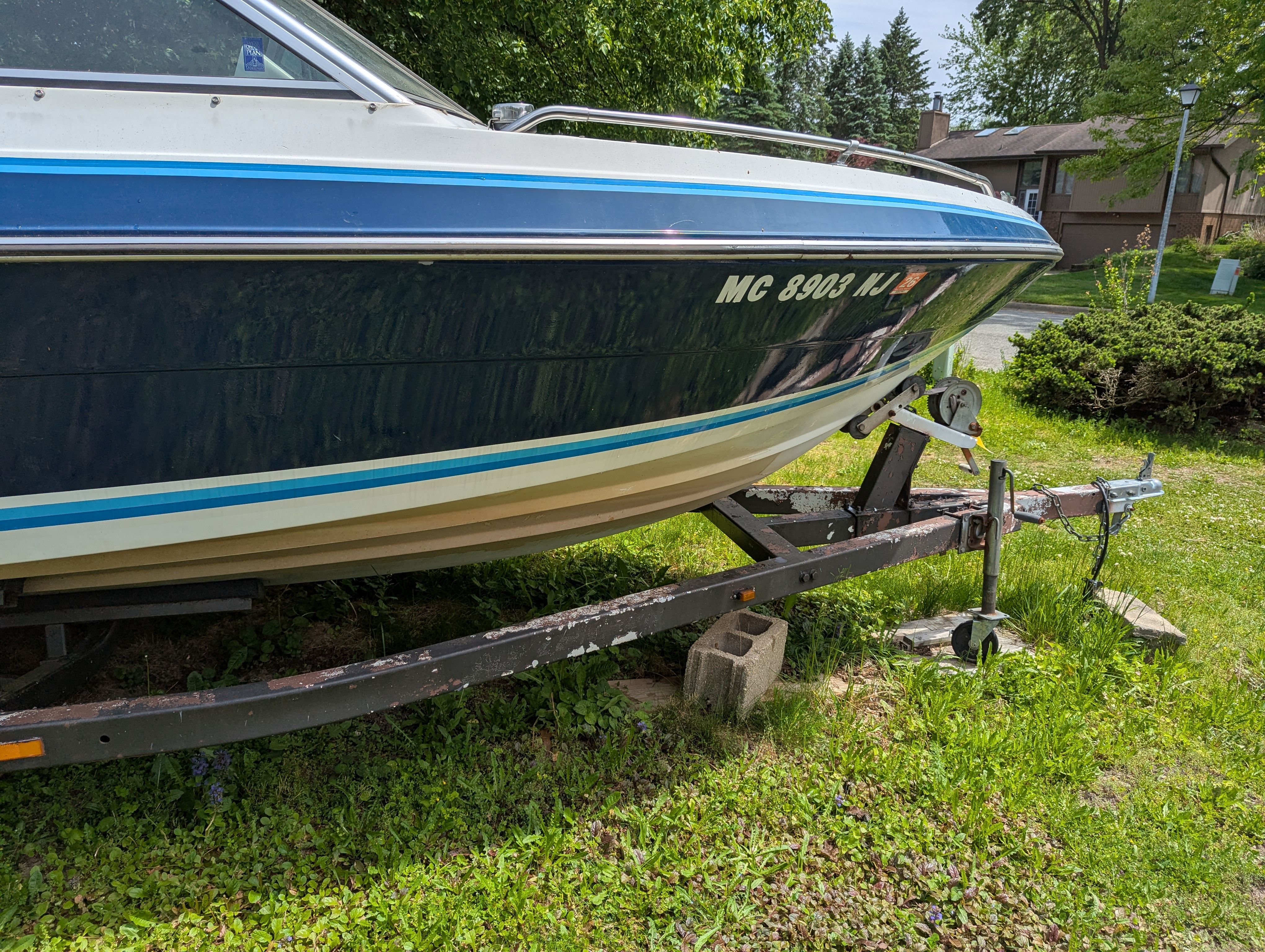 1988 Four Winns 200 Horizon boat on trailer in grassy area.
