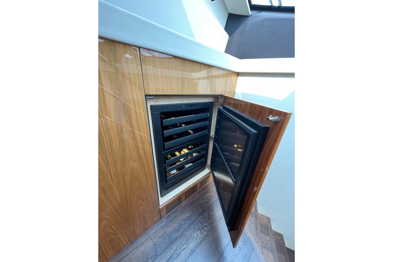 Wine cooler in 2016 Sunseeker Manhattan 65 yacht interior, featuring sleek wood paneling.
