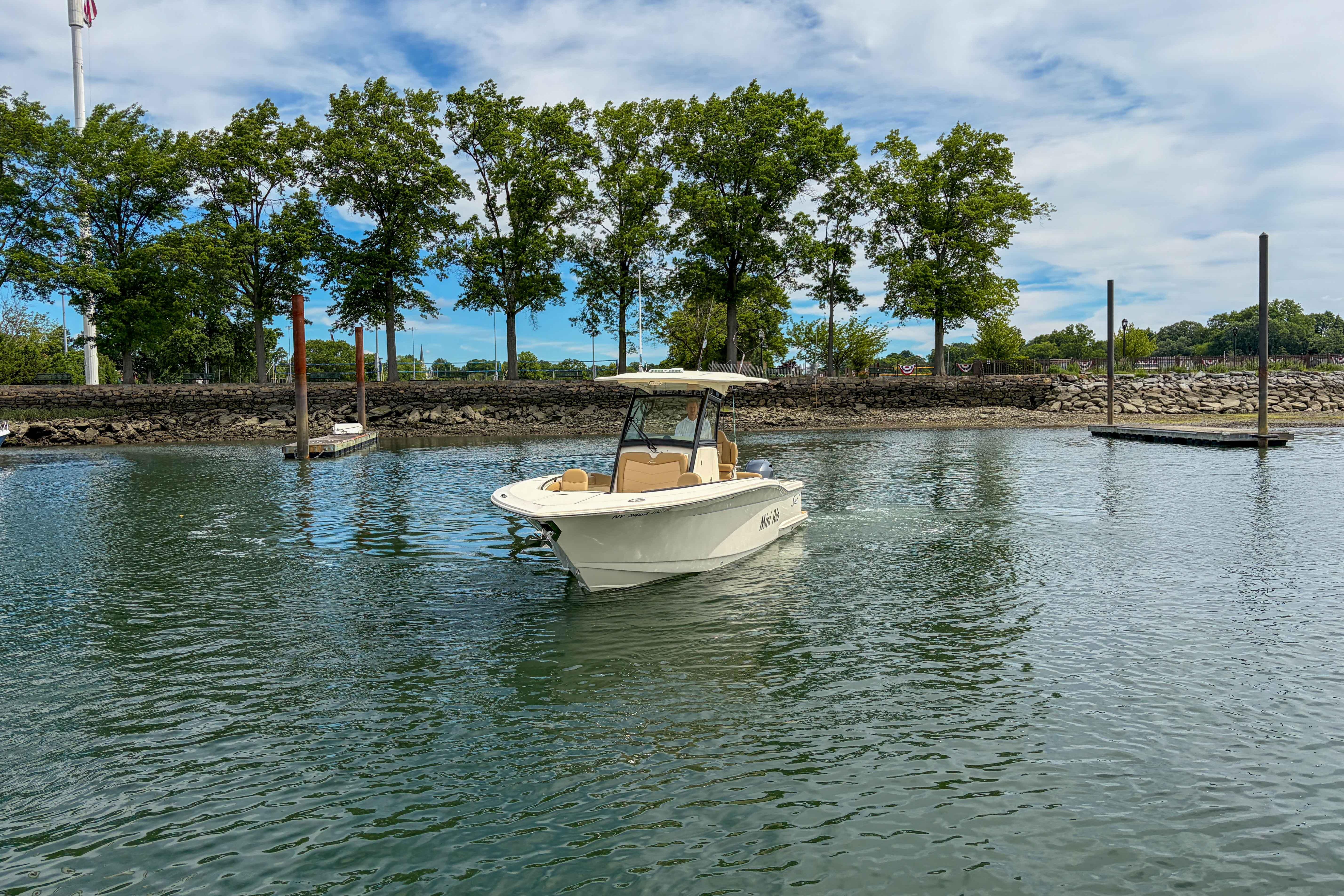 2020 Scout 255 LXF boat cruising on a calm lake with trees in the background.