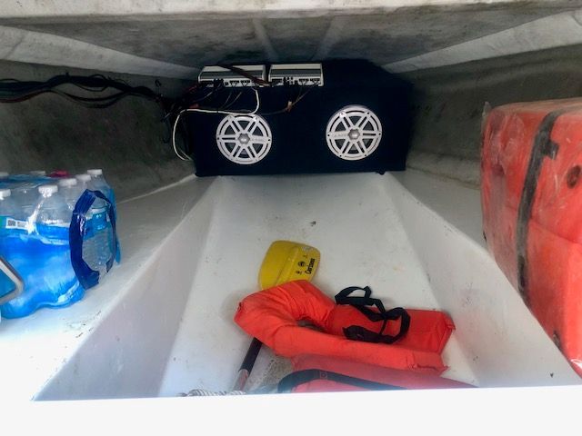 Storage area with life jackets, water bottles, and speakers.
