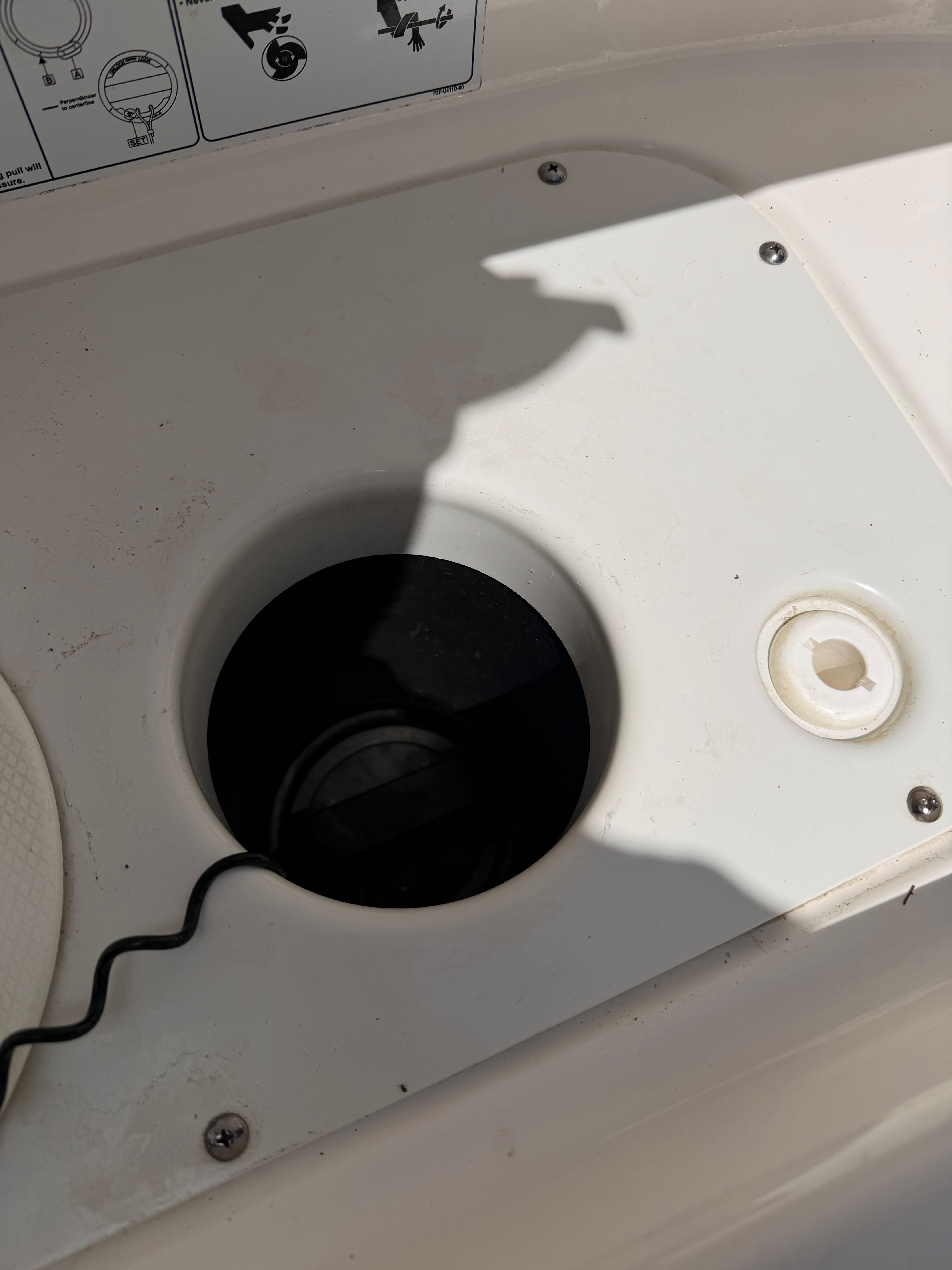 Close-up of a boat deck detail with a round black insert and a white button.