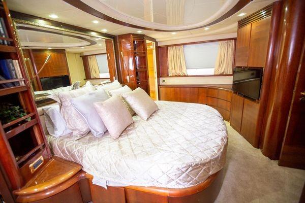 Luxurious bedroom interior of 2003 Azimut 74 Solar yacht with elegant wood finishes.