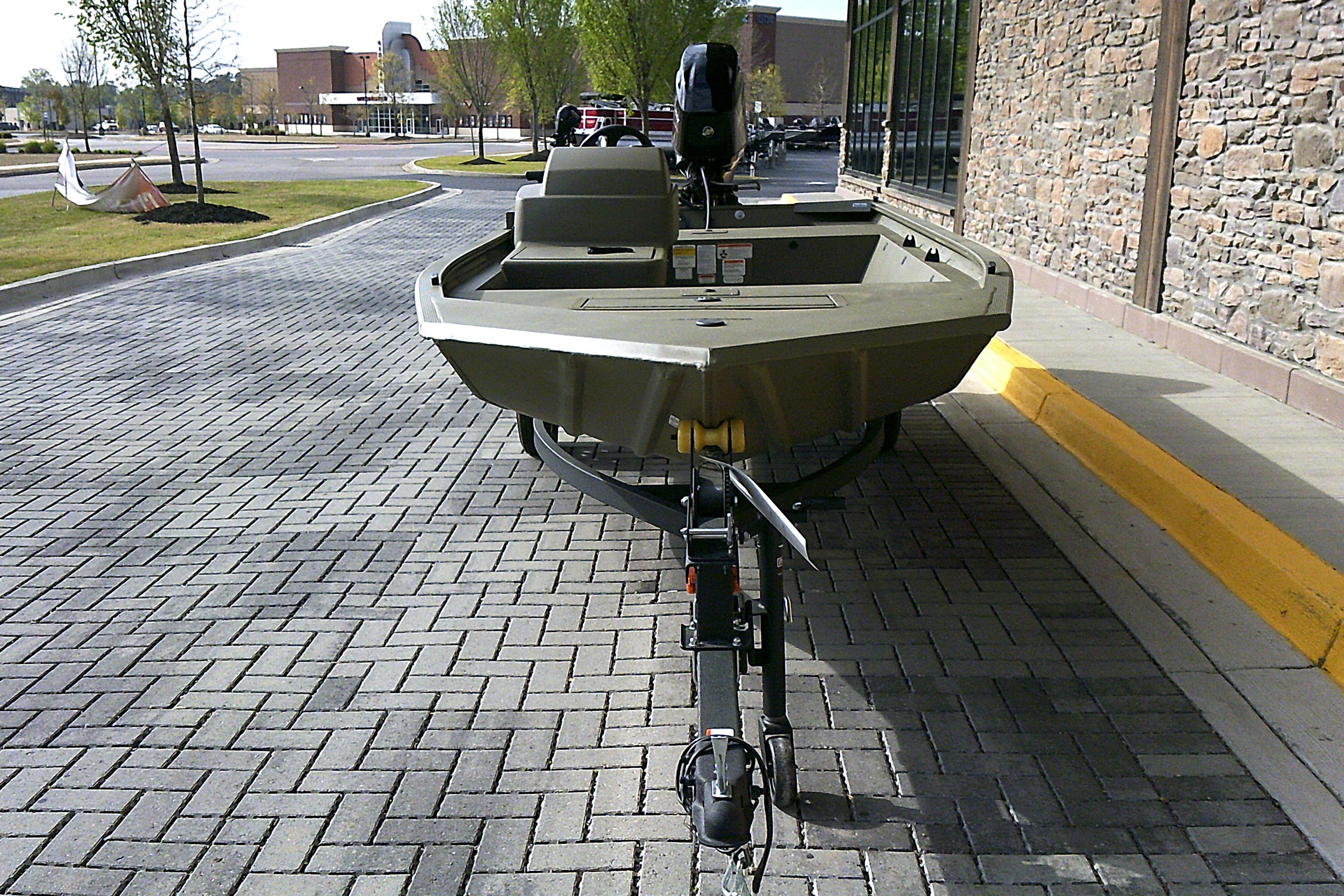 2026 Tracker Grizzly 1648 SC boat on trailer, parked on brick pavement.