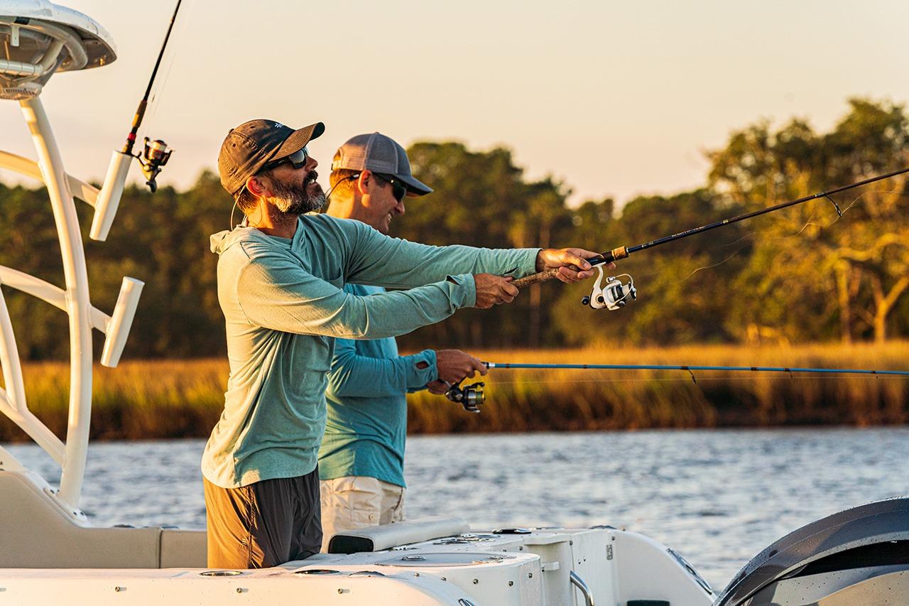 Two people fishing on a 2026 Sailfish 245 DC boat at sunset.