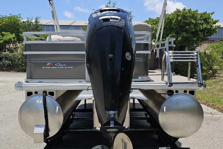 2025 Sun Tracker SportFish 20 DLX pontoon boat with powerful outboard motor, parked outdoors.