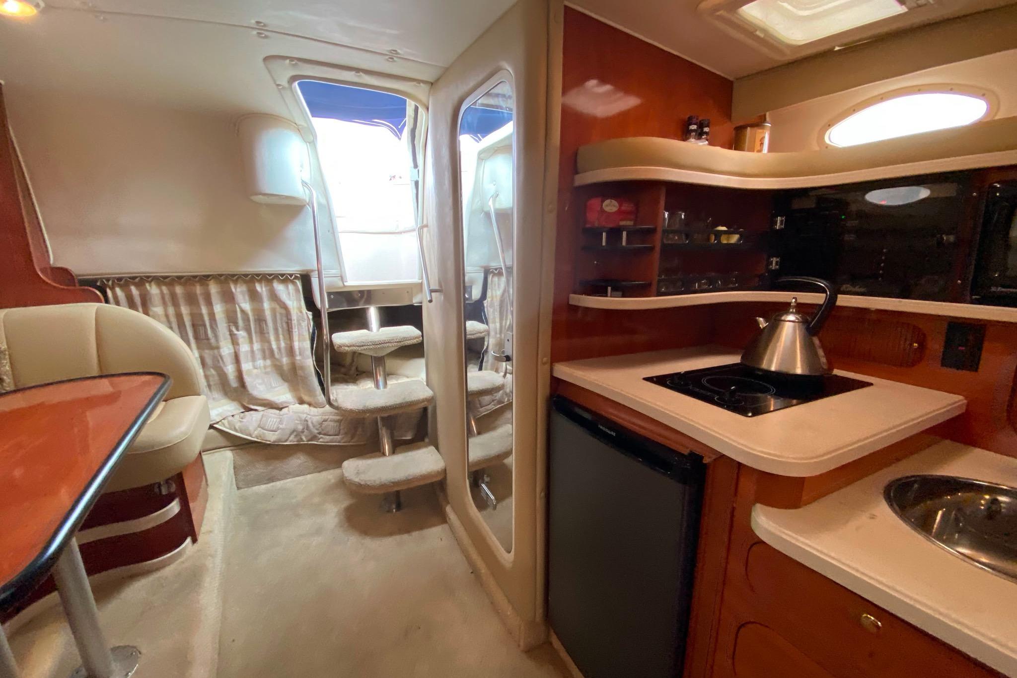 2003 Rinker Fiesta Vee 342 interior with kitchenette, seating, and stairs.