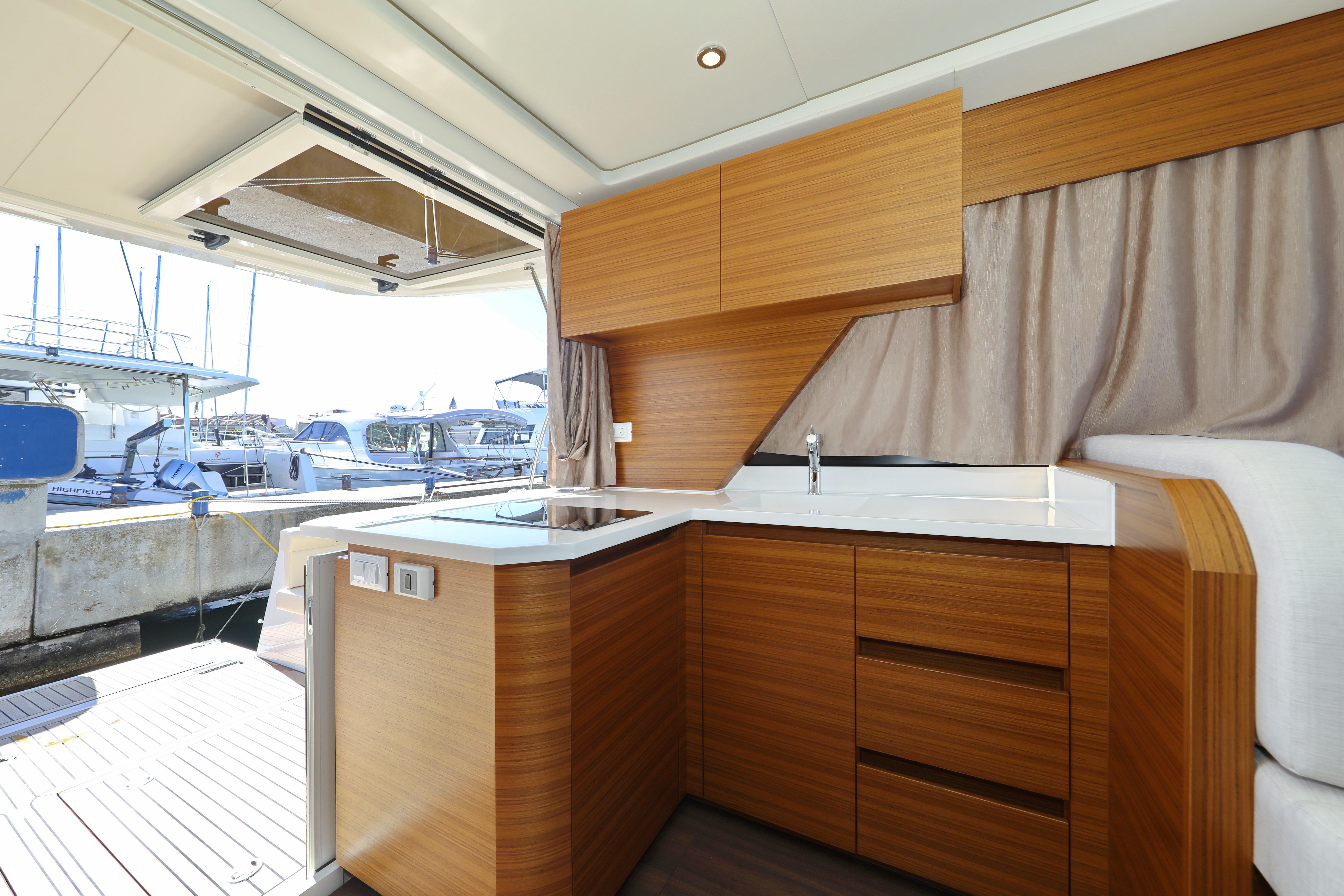 Modern kitchen interior on 2023 Greenline 39 yacht, featuring sleek wood cabinetry and marina view.