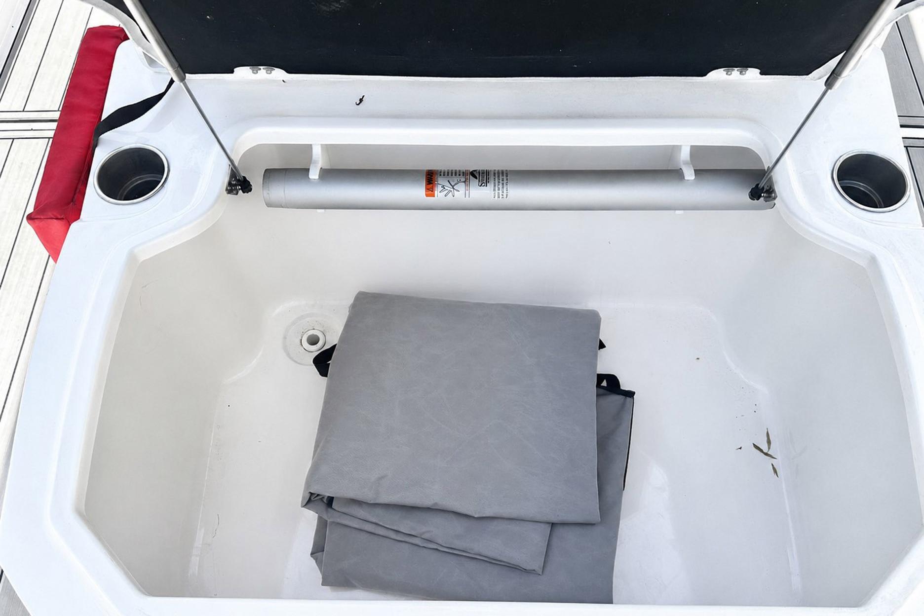 Open storage compartment on a 2002 Sea Fox 228 Commander boat with folded gray cover.