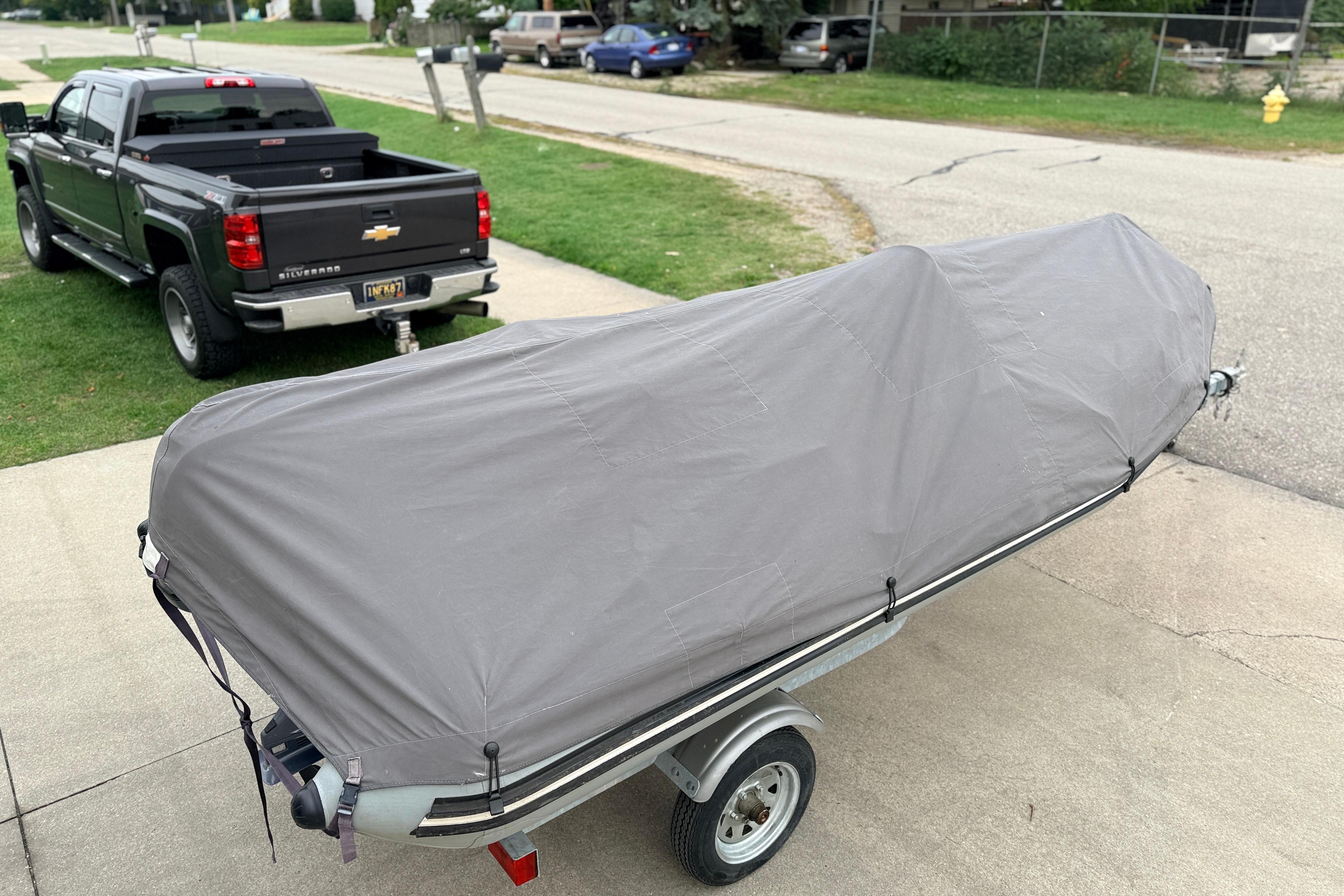 Covered 2014 Zodiac Pro Classic 420 boat on trailer beside a black pickup truck.