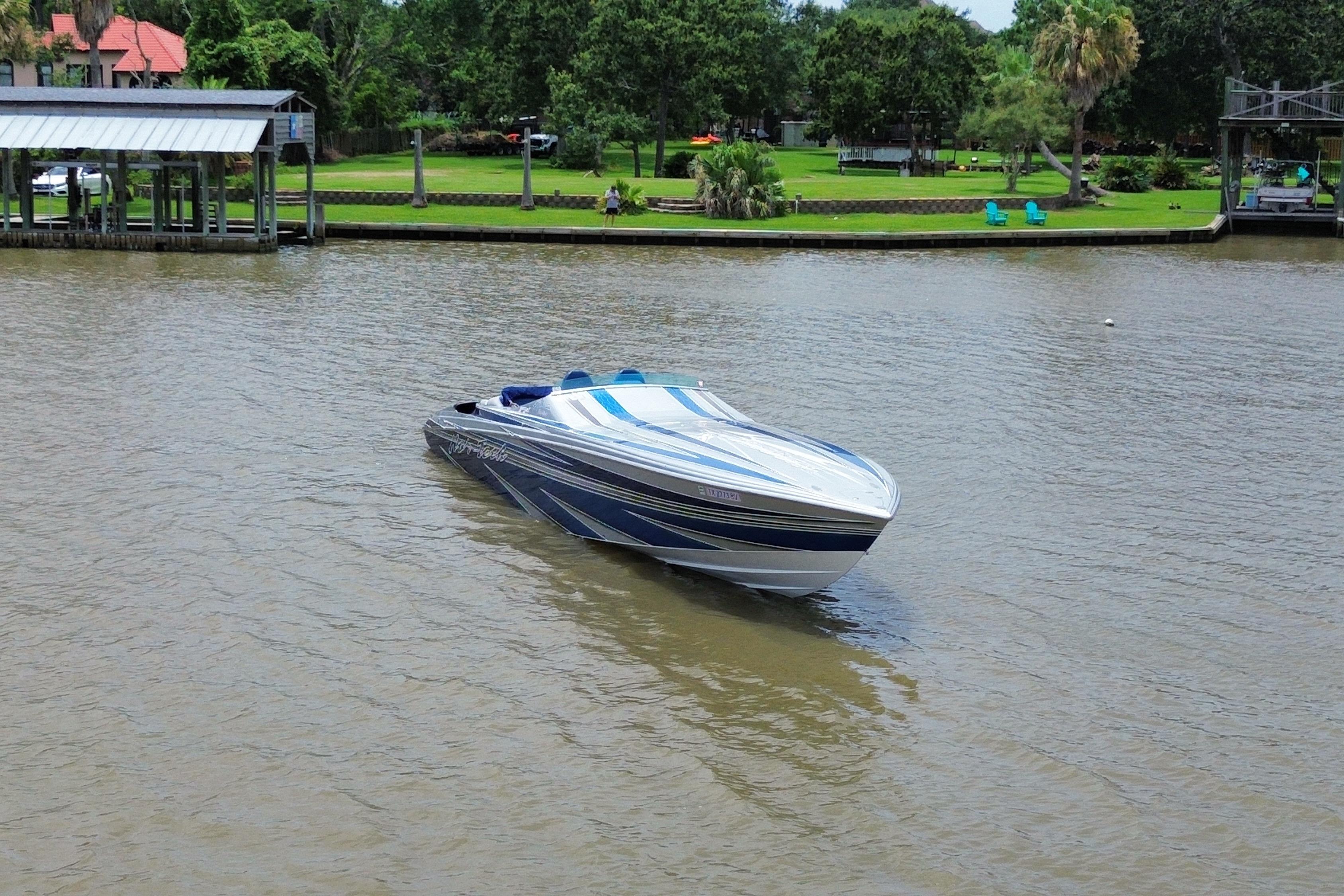 2013 Nor-Tech 477 SPX Vee Bottom boat on a calm river near a green shoreline.