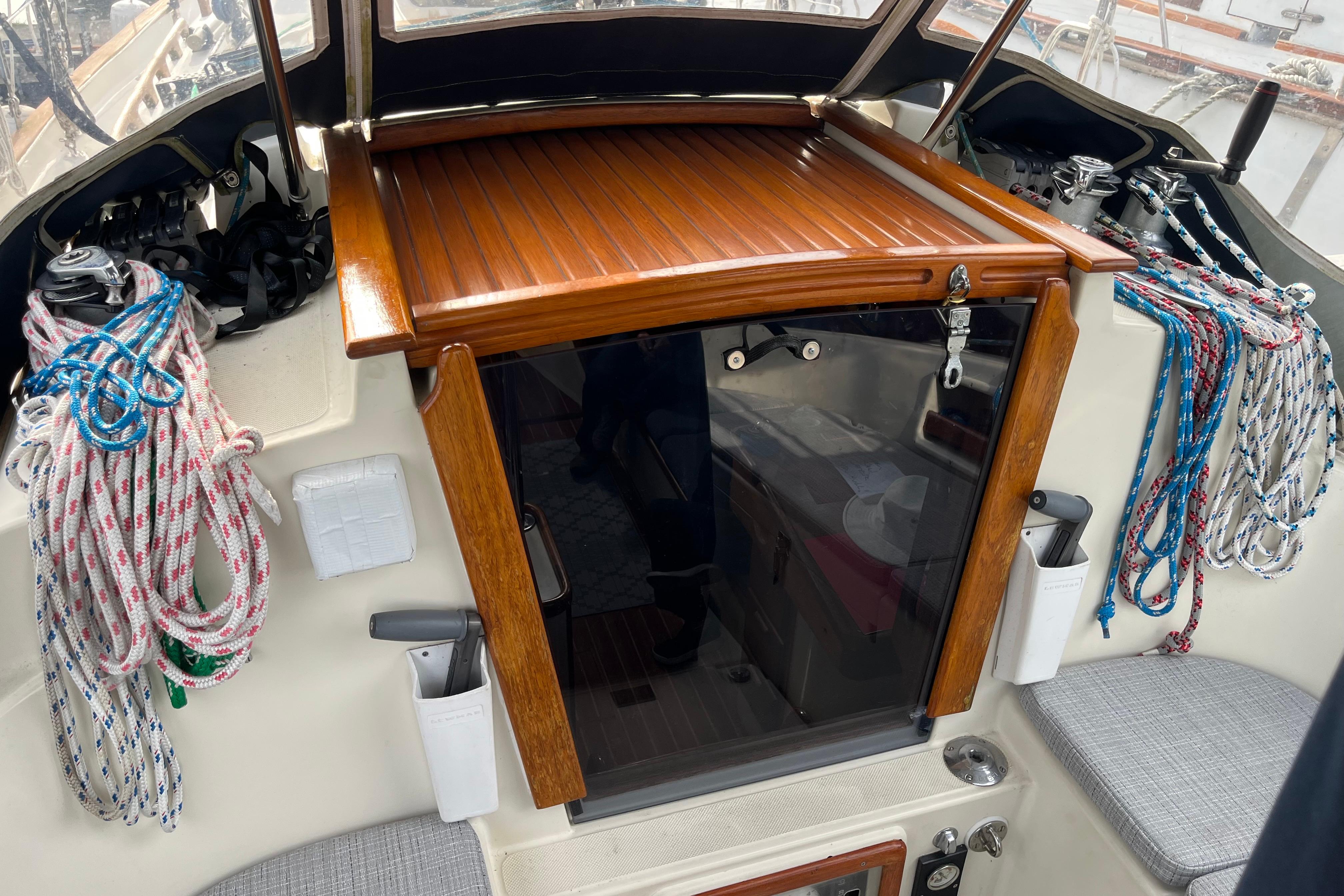 Cockpit of 1997 Pacific Seacraft Crealock 34 sailboat with ropes and wooden hatch.