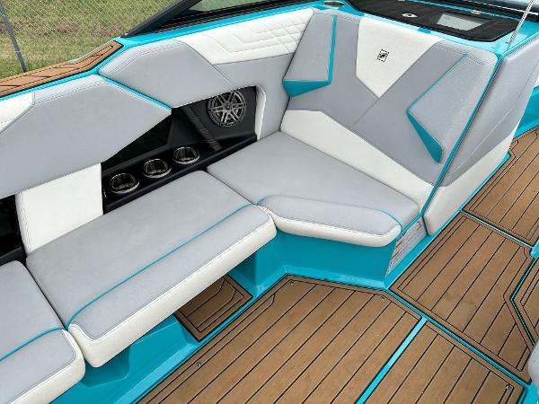 2022 Nautique S23 boat interior with gray and white seating, teal accents, and teak flooring.