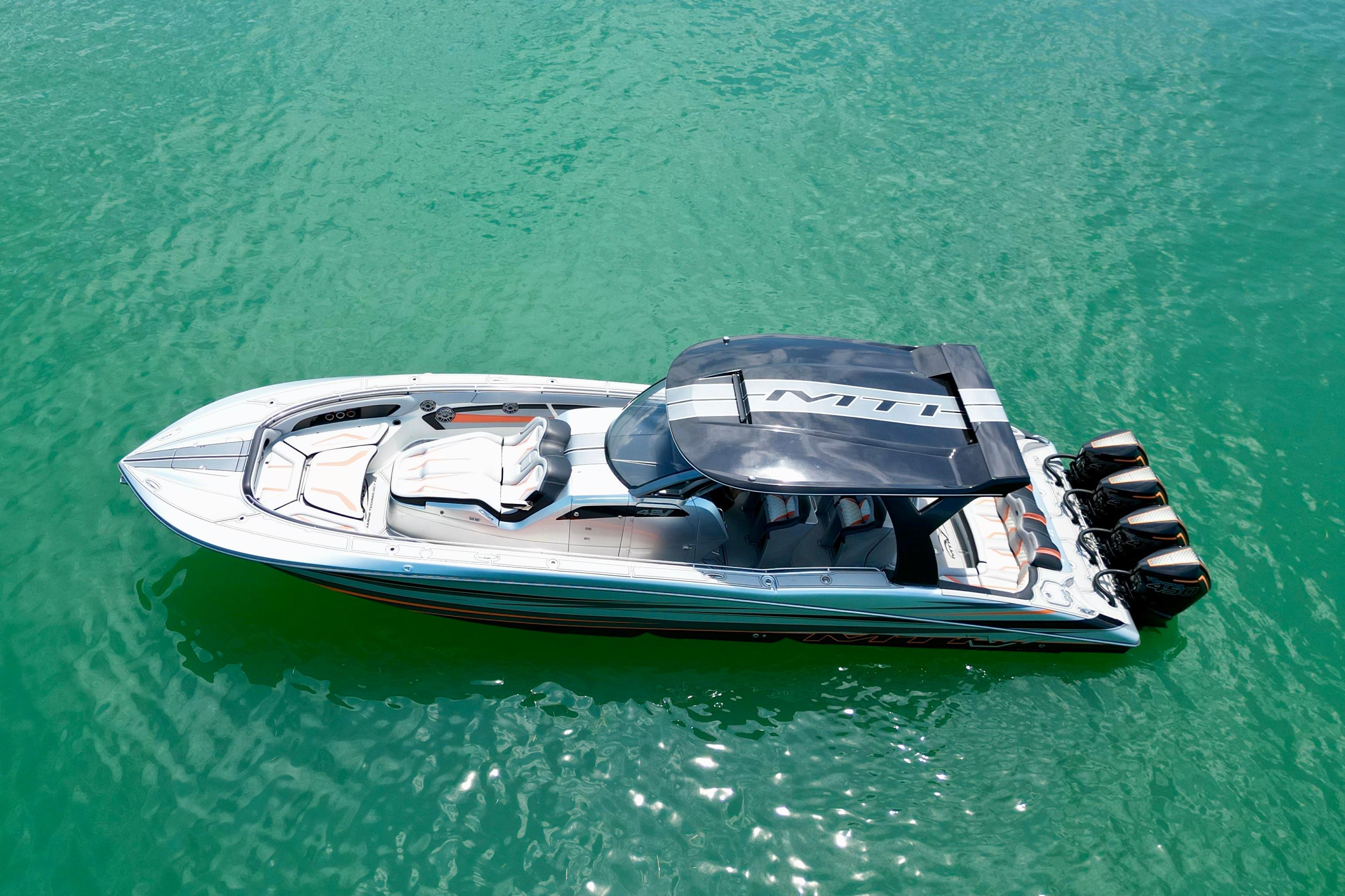 2017 MTI V42 boat with canopy on turquoise water, featuring multiple outboard engines.