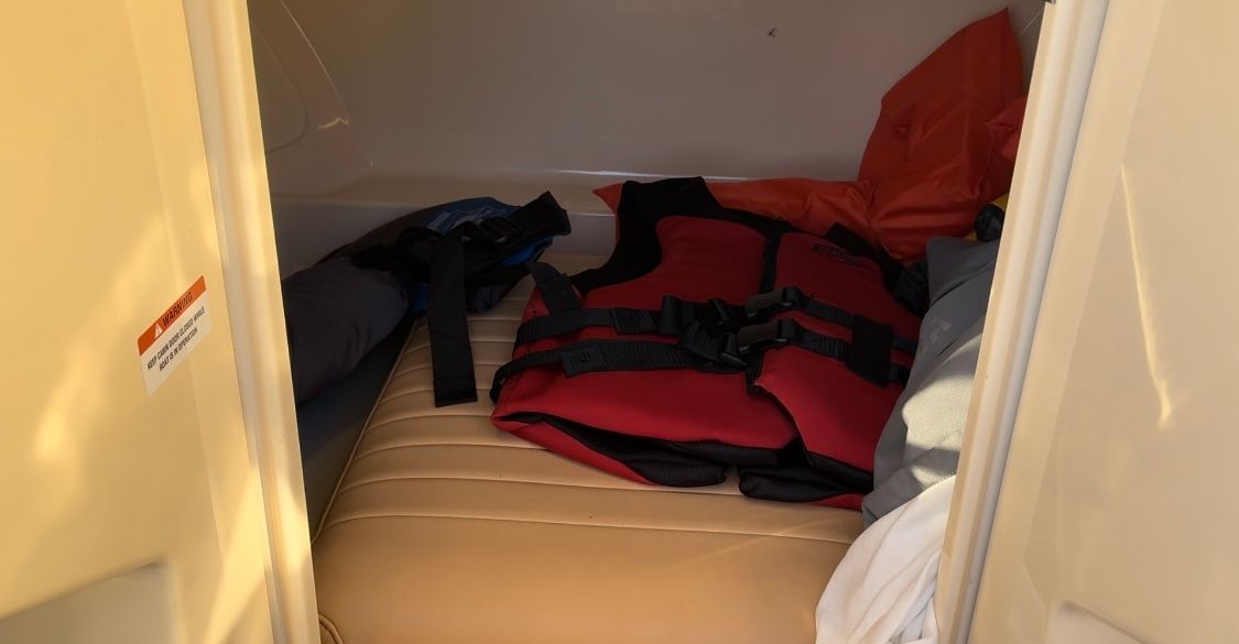 A cozy interior with a cushioned berth and a red life jacket.
