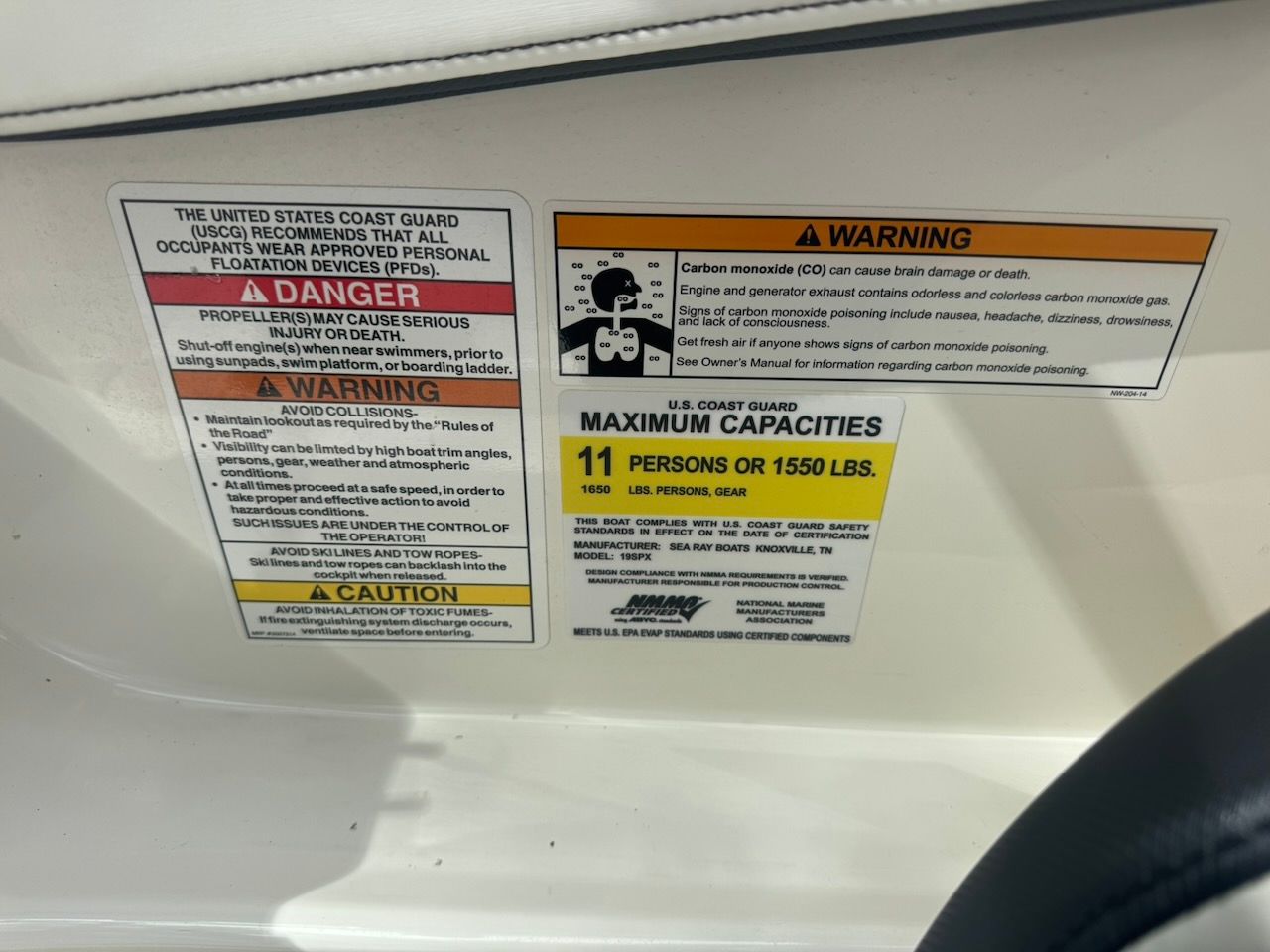 Safety and warning labels on a boat, including capacity limits and carbon monoxide warning.