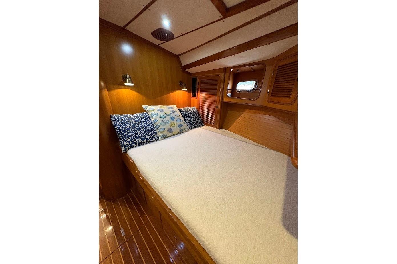 Cozy cabin interior of 1997 Taswell 50 yacht with wooden finish and decorative pillows.
