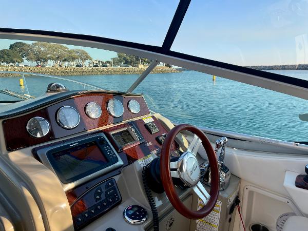 2014 Sea Ray 330 Sundancer cockpit with navigation instruments, steering wheel, and scenic water view.