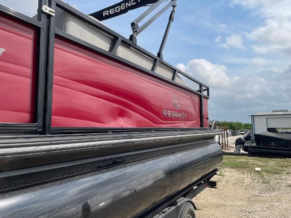 2023 Regency 250DL3 pontoon boat with red and black exterior, parked outdoors.