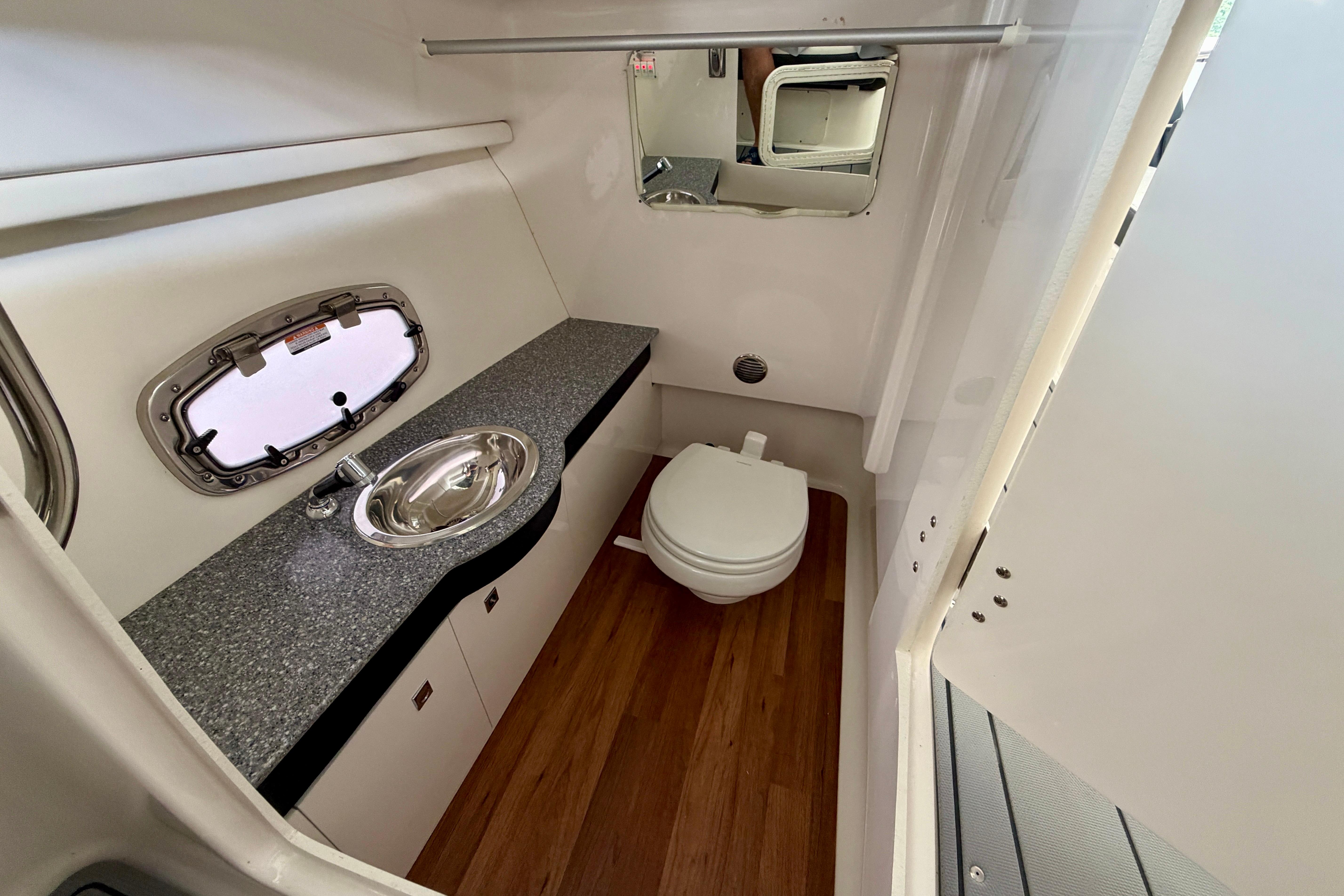 2022 Chaparral 317 SSX boat bathroom with sink, toilet, and wood flooring.