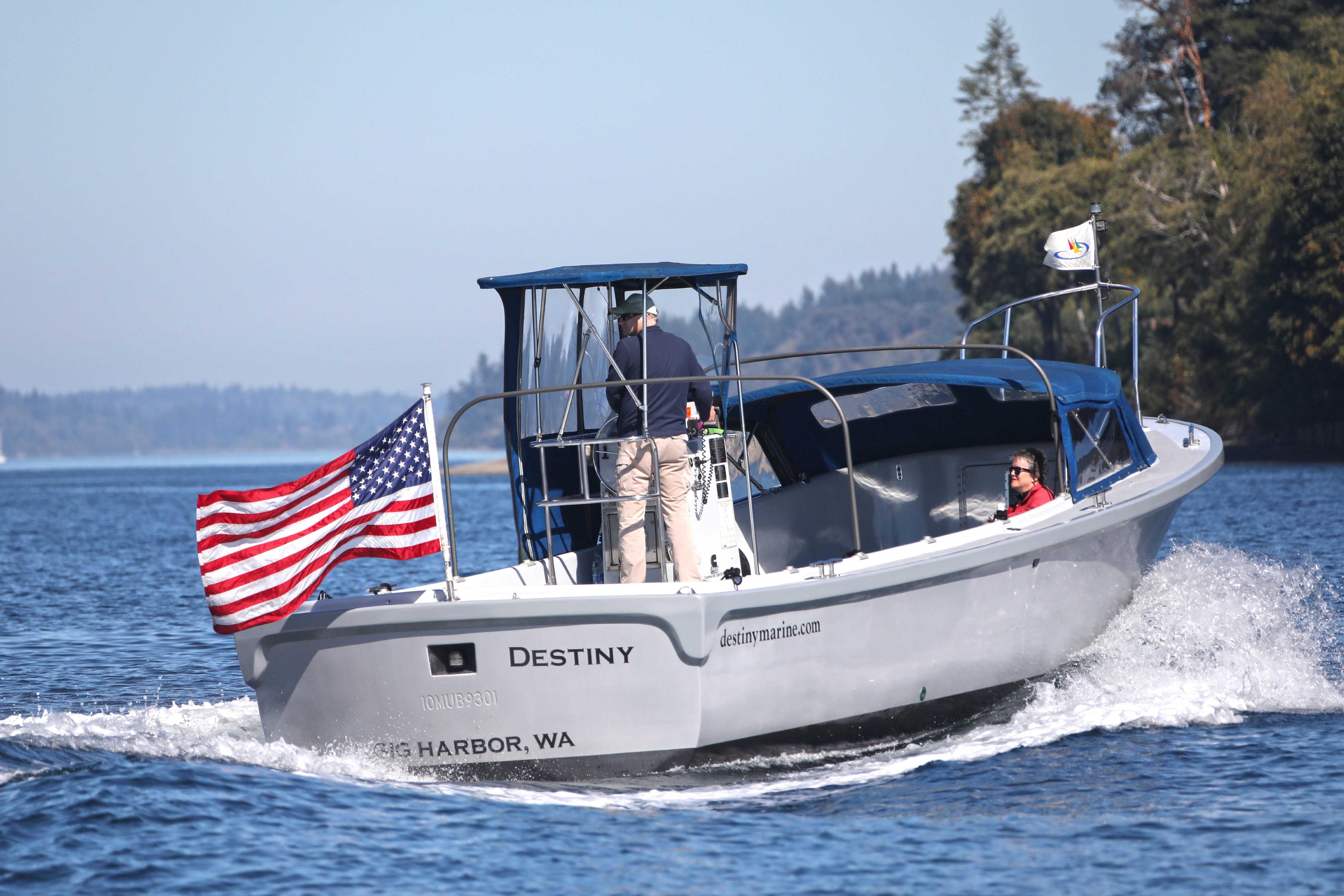 Boat named "Destiny" with American flag cruising on a scenic waterway.