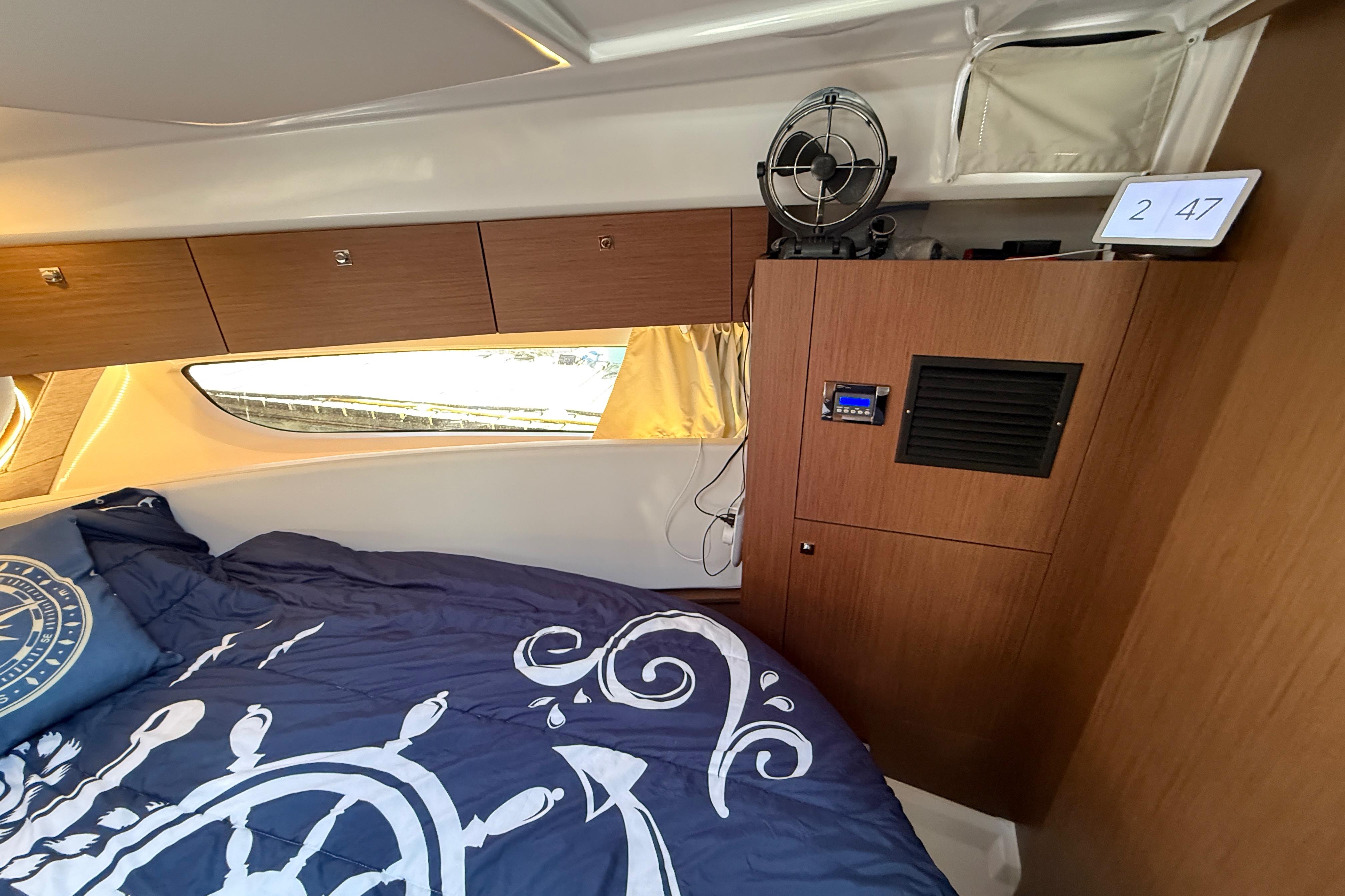 Interior cabin of 2022 Jeanneau NC 1095 Fly with nautical-themed bedding and wood cabinetry.