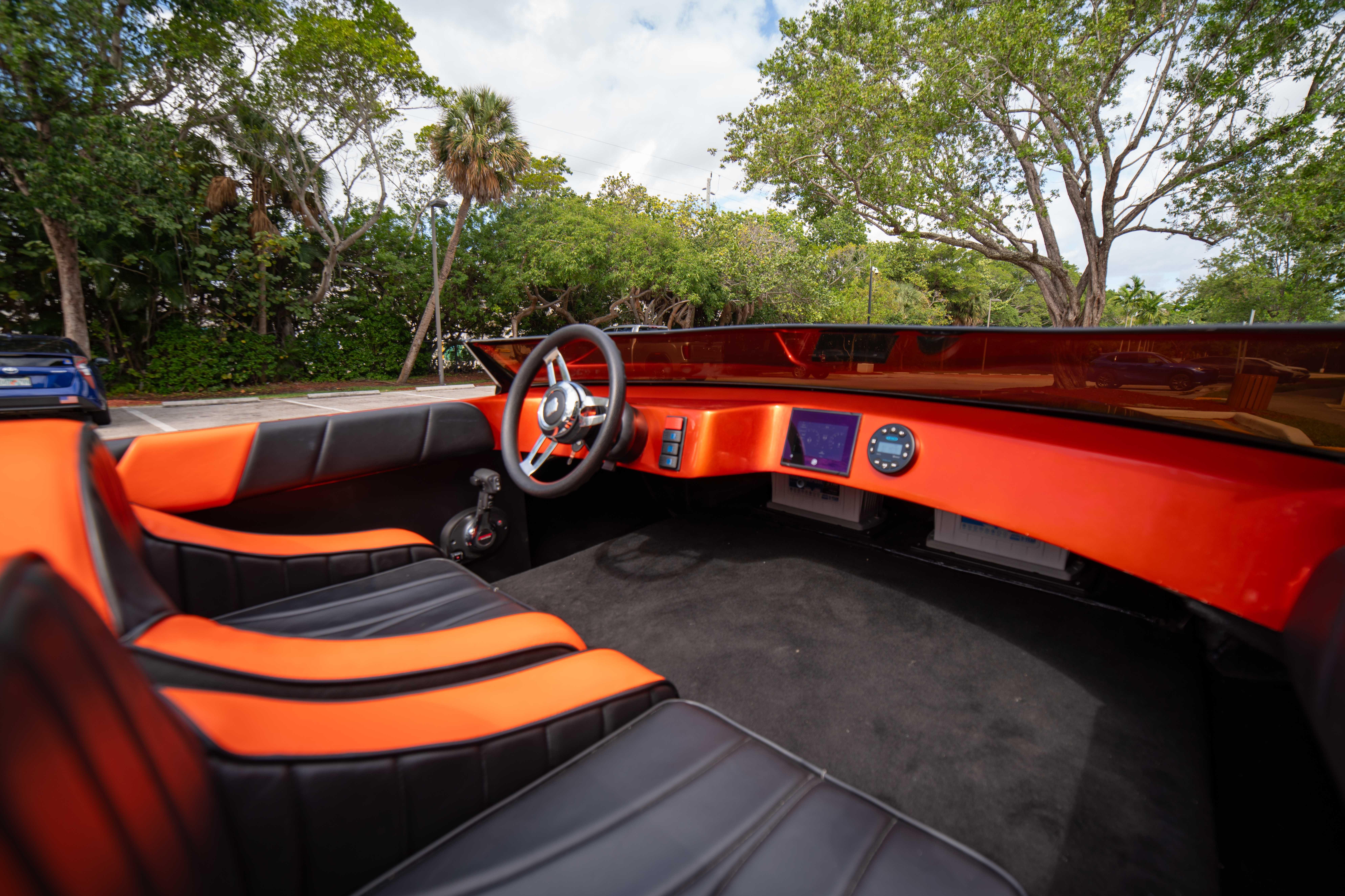 1984 Sleekcraft Aristocrat 20 boat interior with orange and black seating, steering wheel, and dashboard.