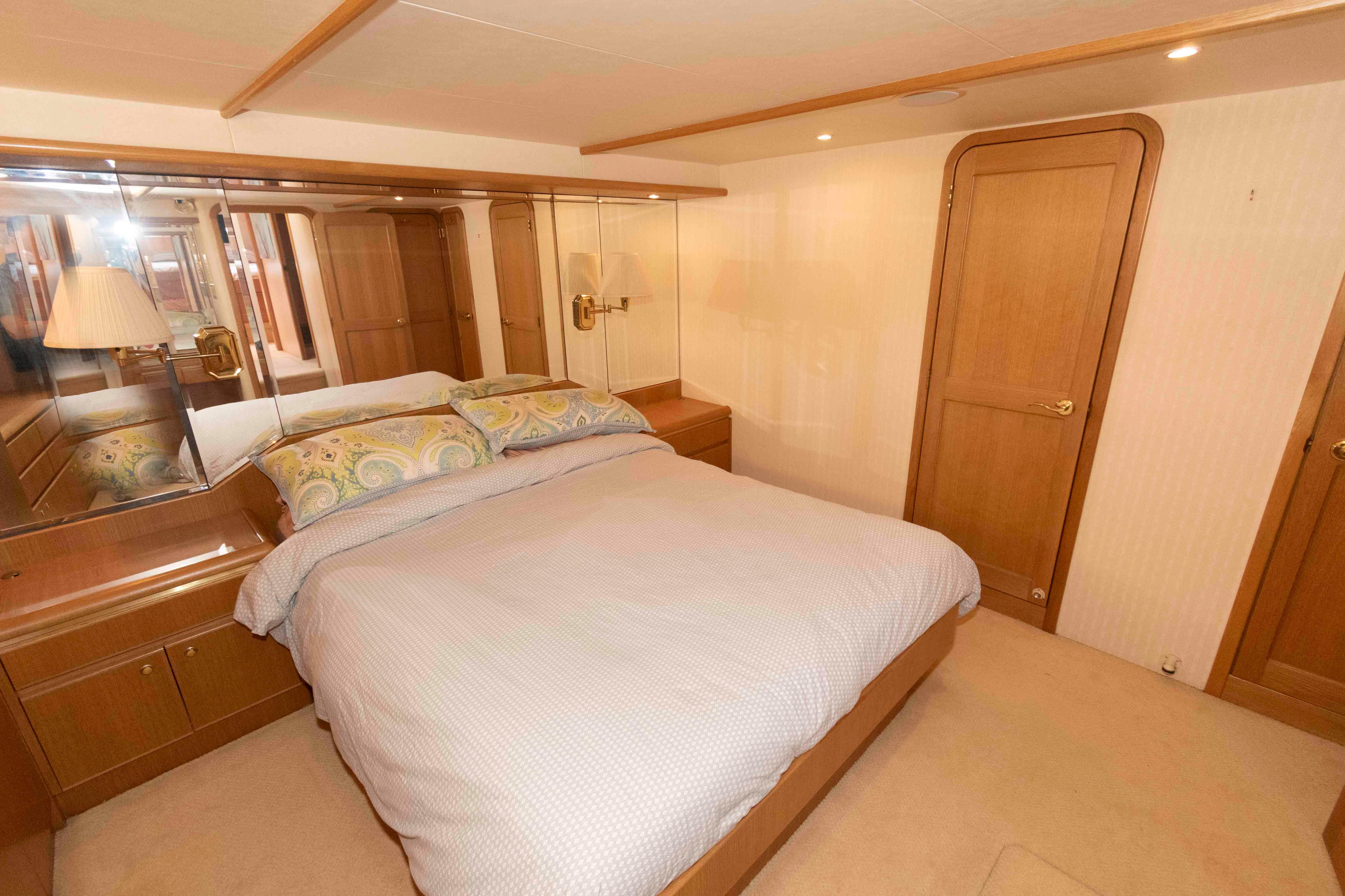 Luxurious bedroom in 1999 West Bay 58 Sonship Pilothouse yacht with elegant wood finishes.