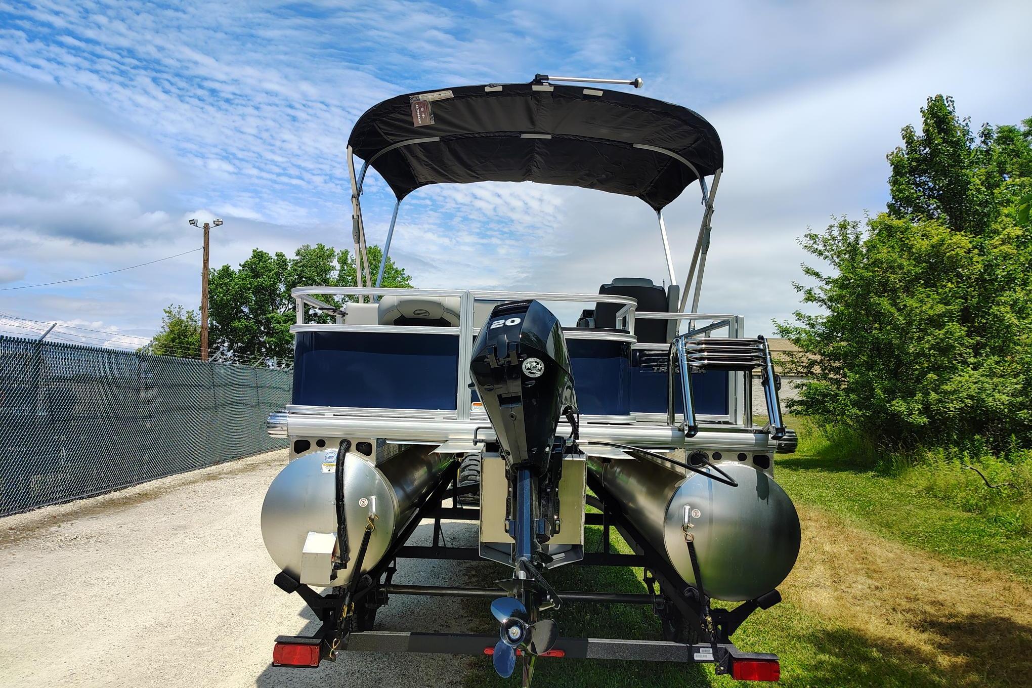 2026 Sun Tracker Bass Buggy 18 DLX pontoon boat with canopy, parked outdoors.