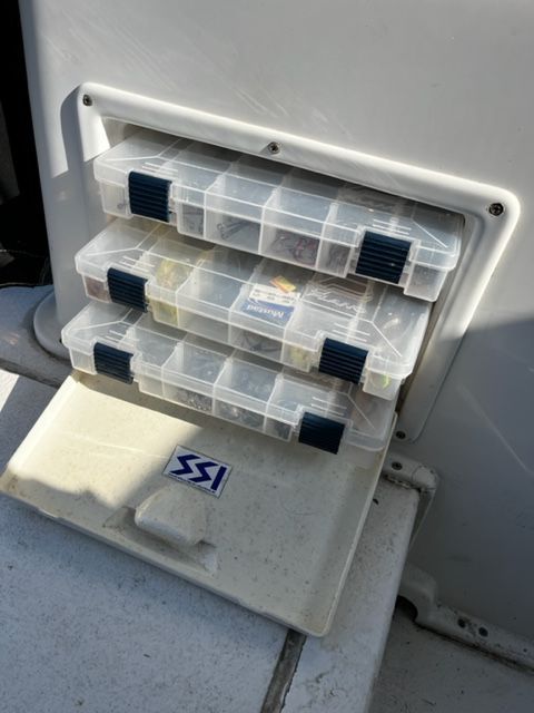 Three transparent plastic boxes are stored in a compartment on a Sport-Craft 252 SPORT FISH boat.