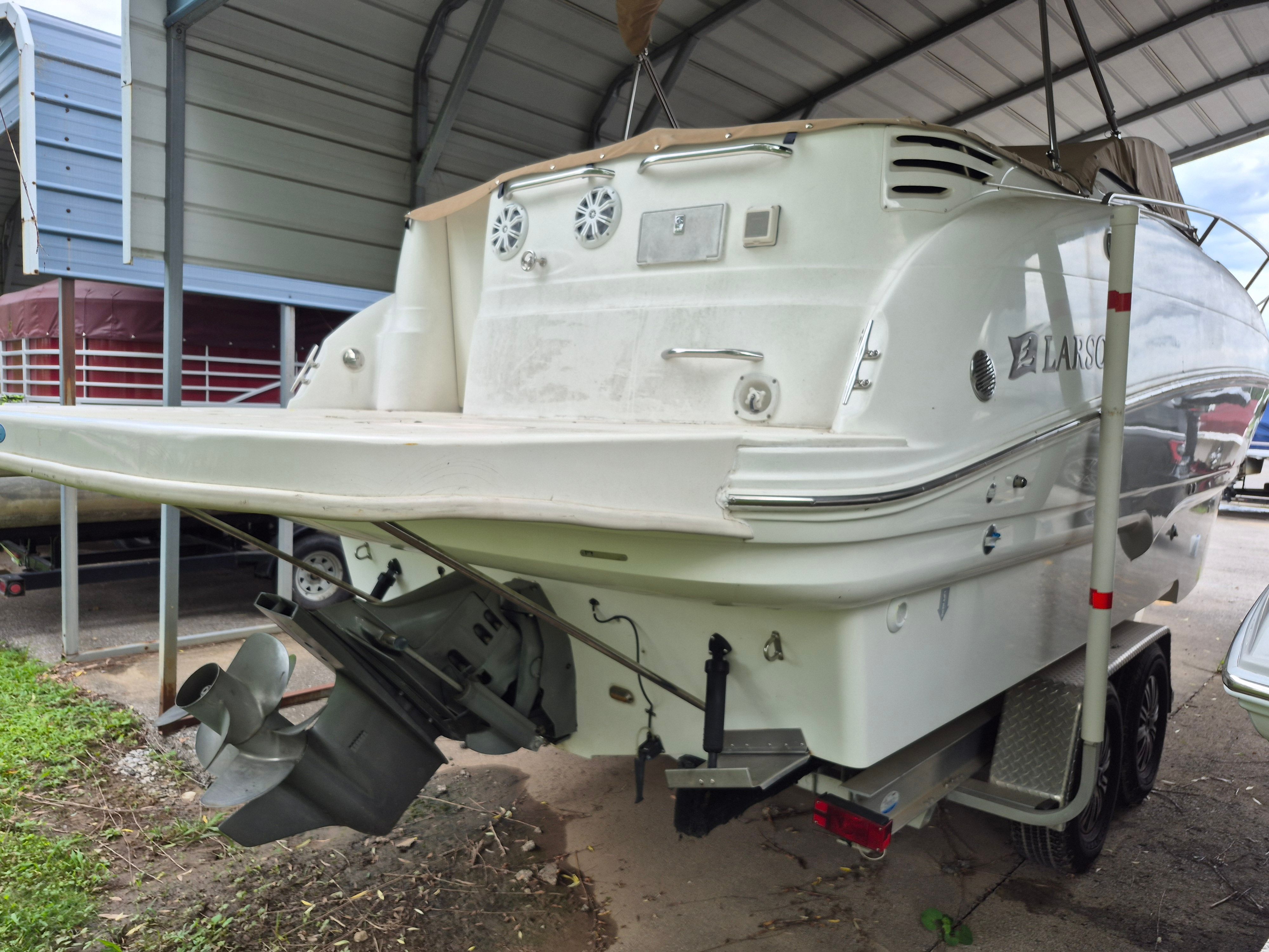 Rear view of a 2004 Larson Cabrio 274 under a shelter.