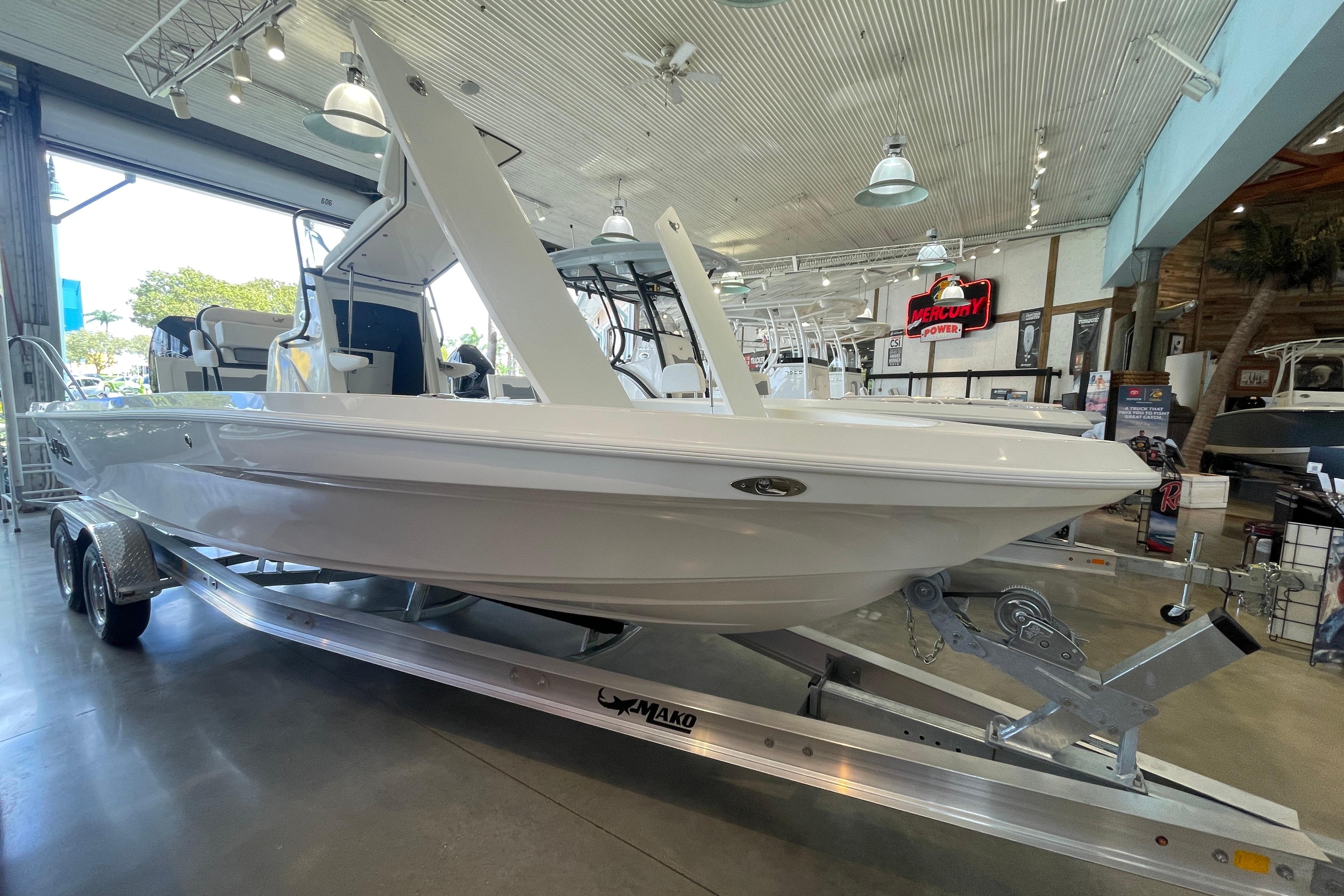 2026 Mako 24 APEX boat displayed in a showroom on a trailer.