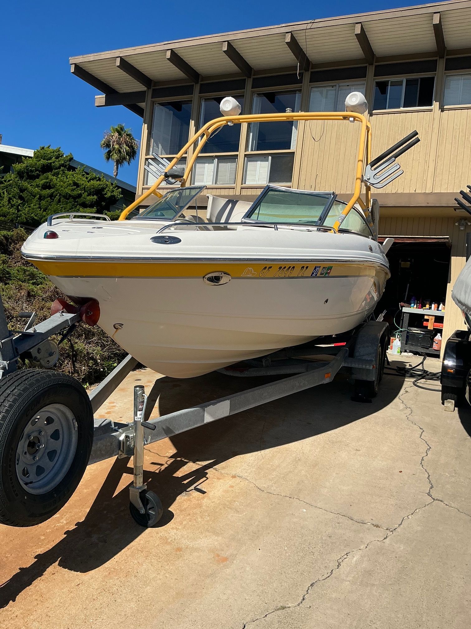 A 2003 Chaparral 210 SS boat on a trailer in front of a modern building.