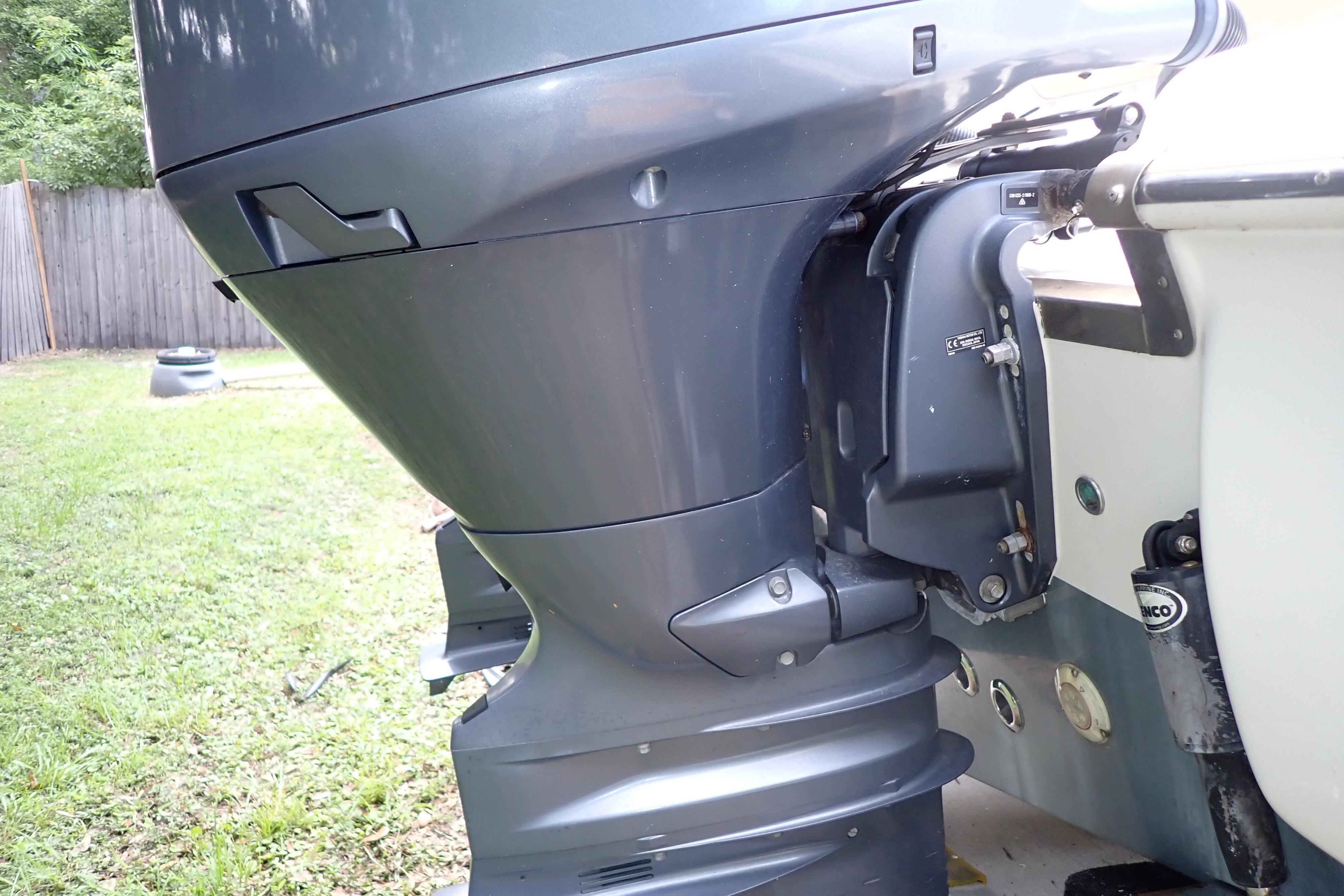 Close-up of a 2019 Key West 263 FS boat's outboard motor in a grassy yard.