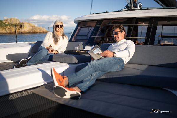 Couple relaxing on 2025 Nautitech 48 Open yacht deck, enjoying sunny day.