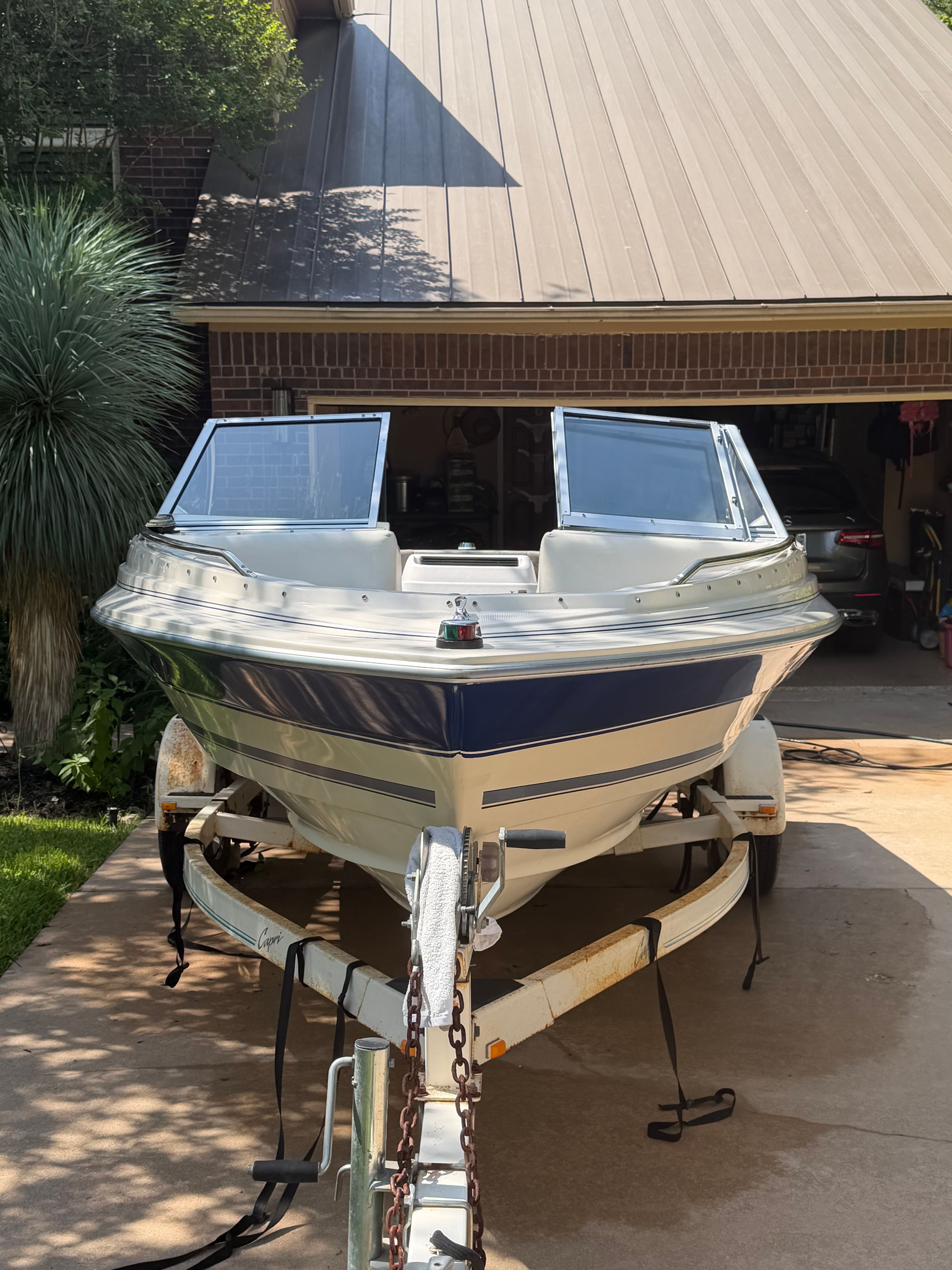 A 1994 Bayliner CAPRI on a trailer in front of a garage.