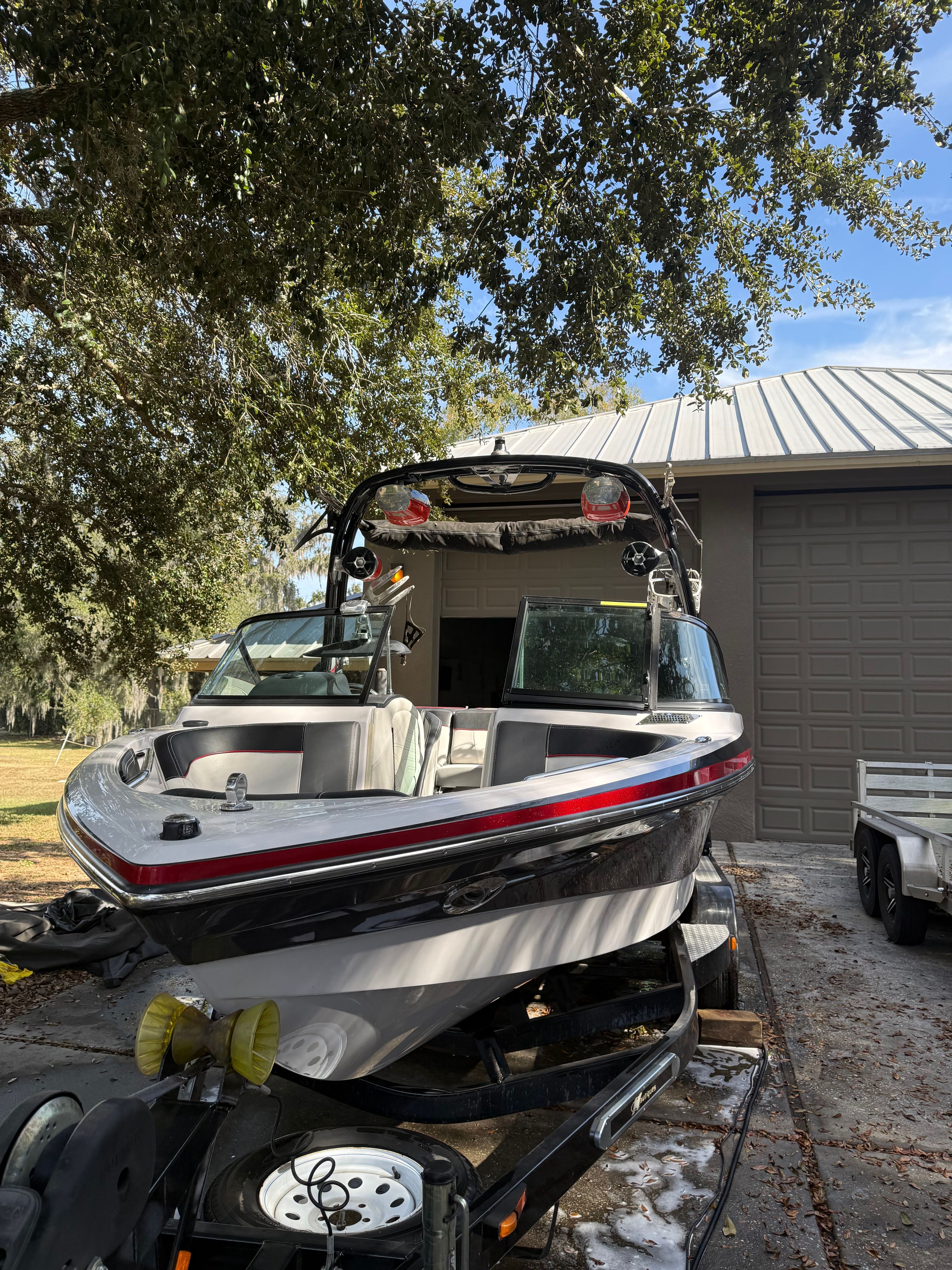 2012 Nautique Super Air Nautique 210 boat on trailer in front of garage.