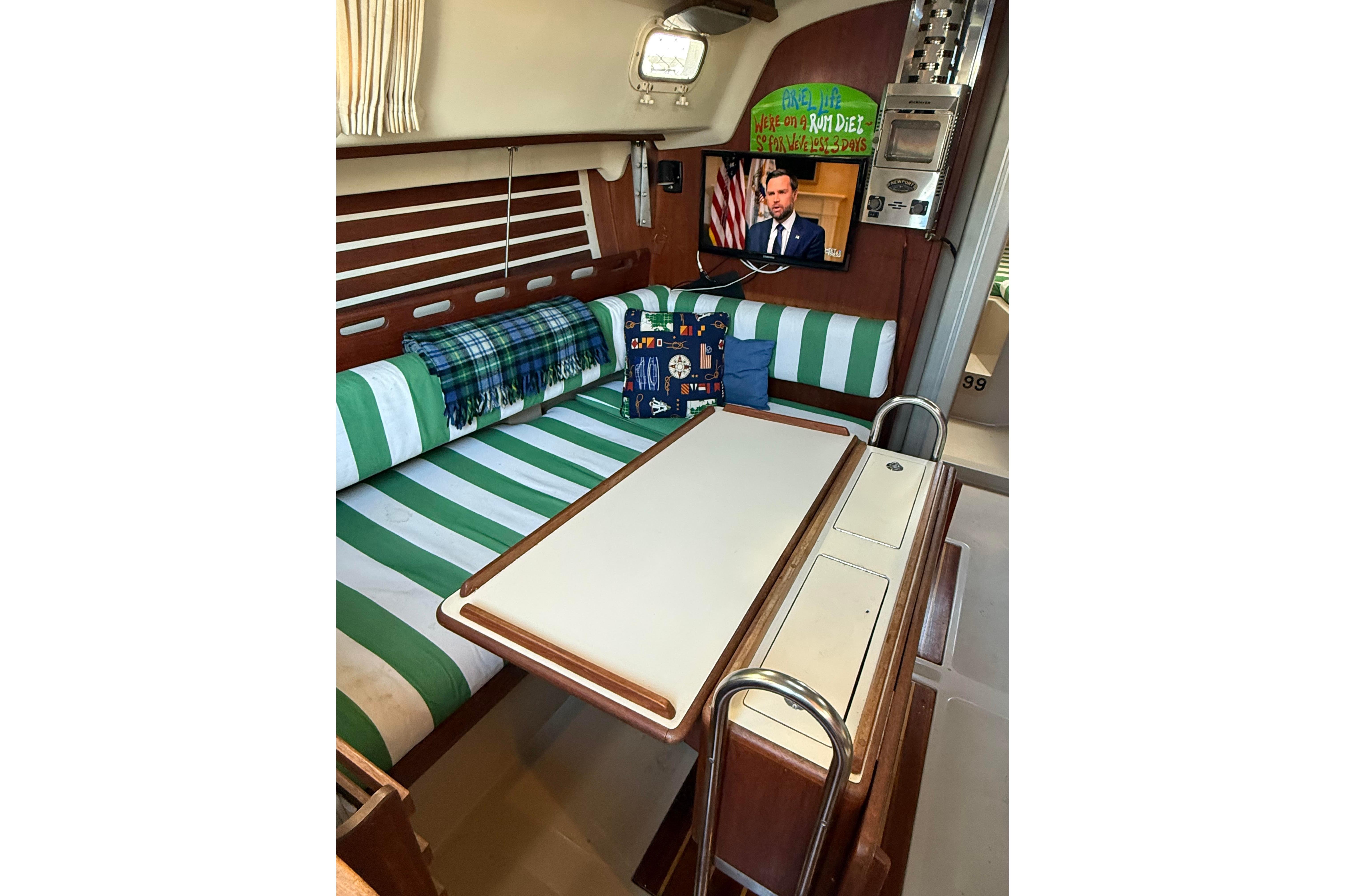 Interior of a 1983 O'Day 34 sailboat with striped seating and a mounted TV.