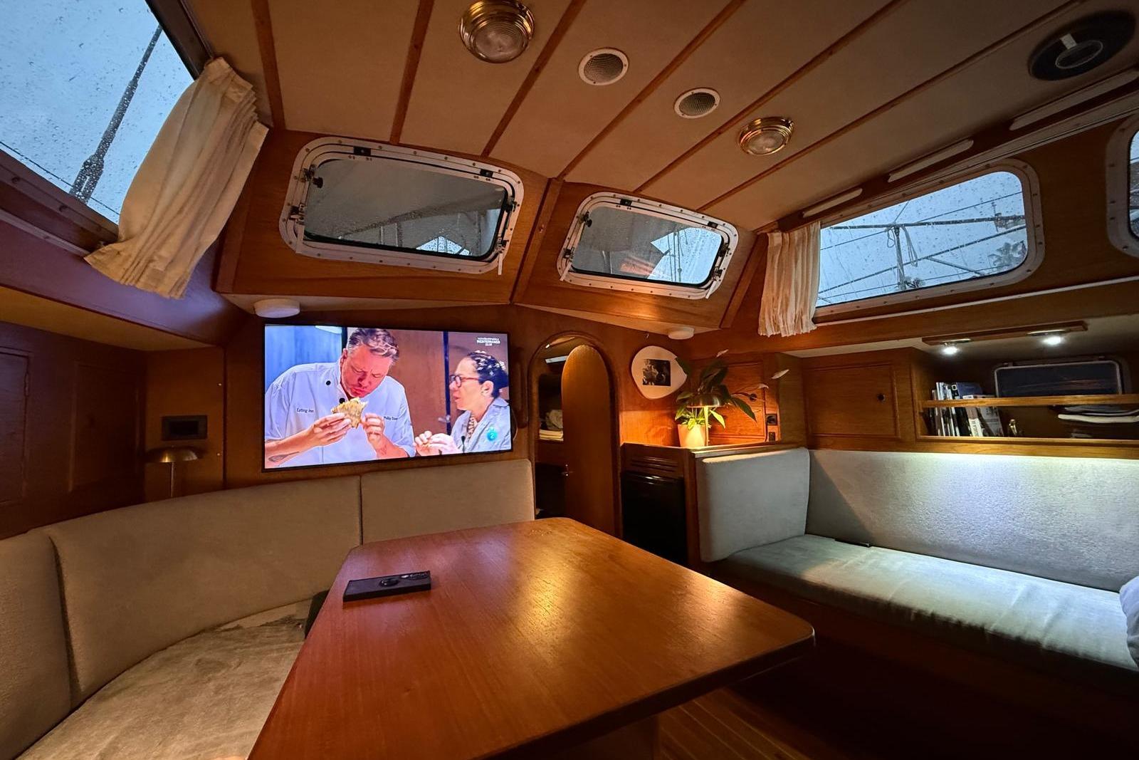 Cozy interior of a 1985 Oyster 435 yacht with a TV and seating area.