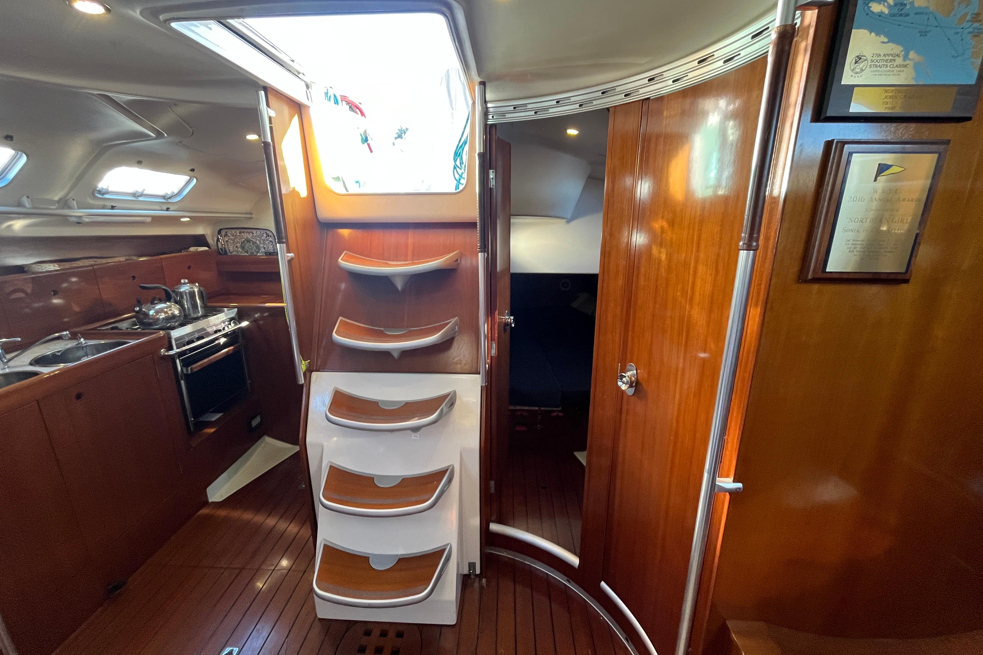 Interior of 1991 Beneteau First 45f5 yacht with wooden cabinetry and compact kitchen.