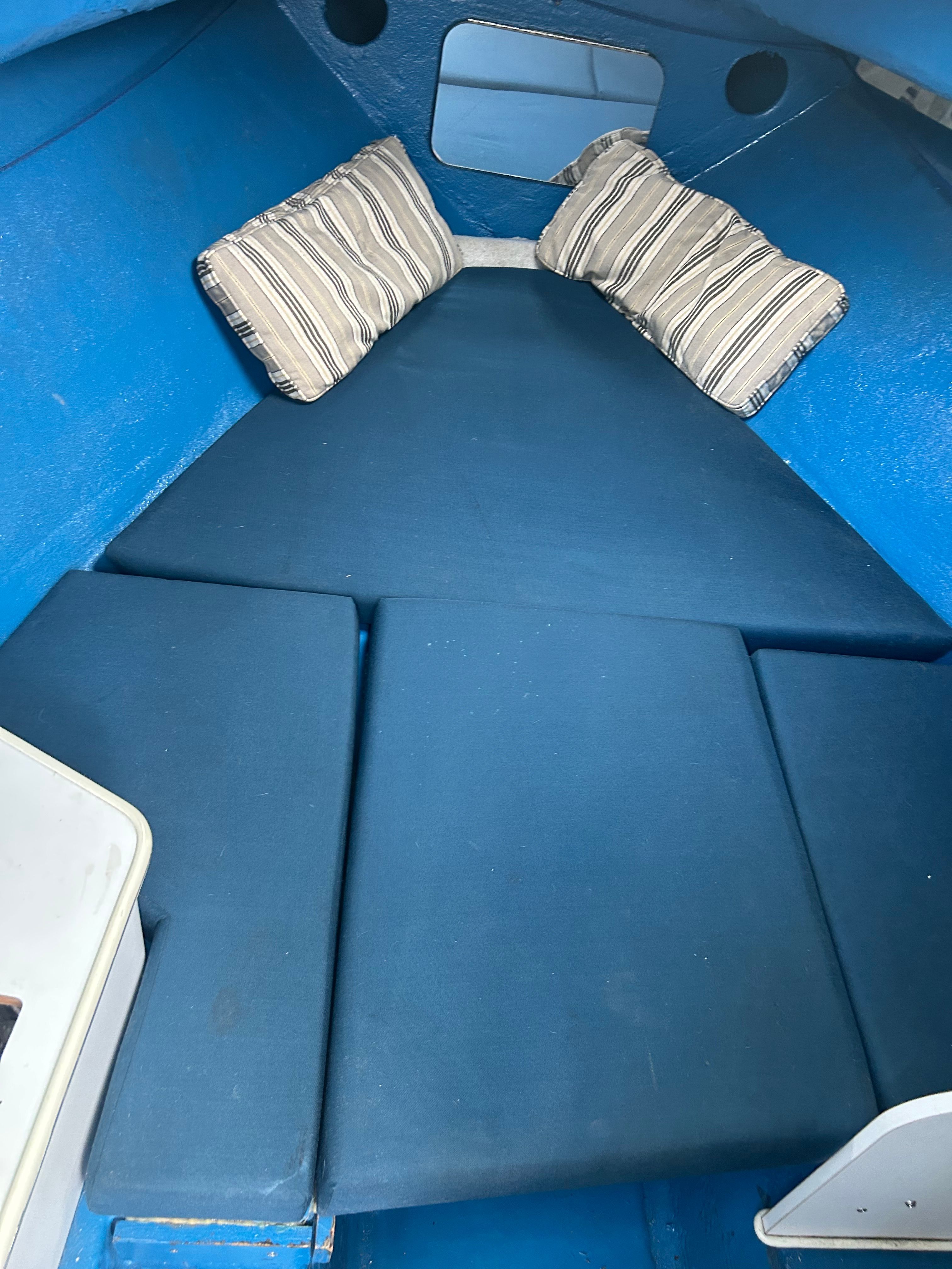 Interior of a 2002 Wellcraft 24 Walkaround with blue cushions and striped pillows.