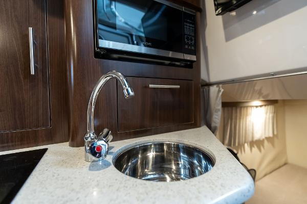 Compact kitchen area in a 2016 Regal 28 Express boat with sink and microwave.