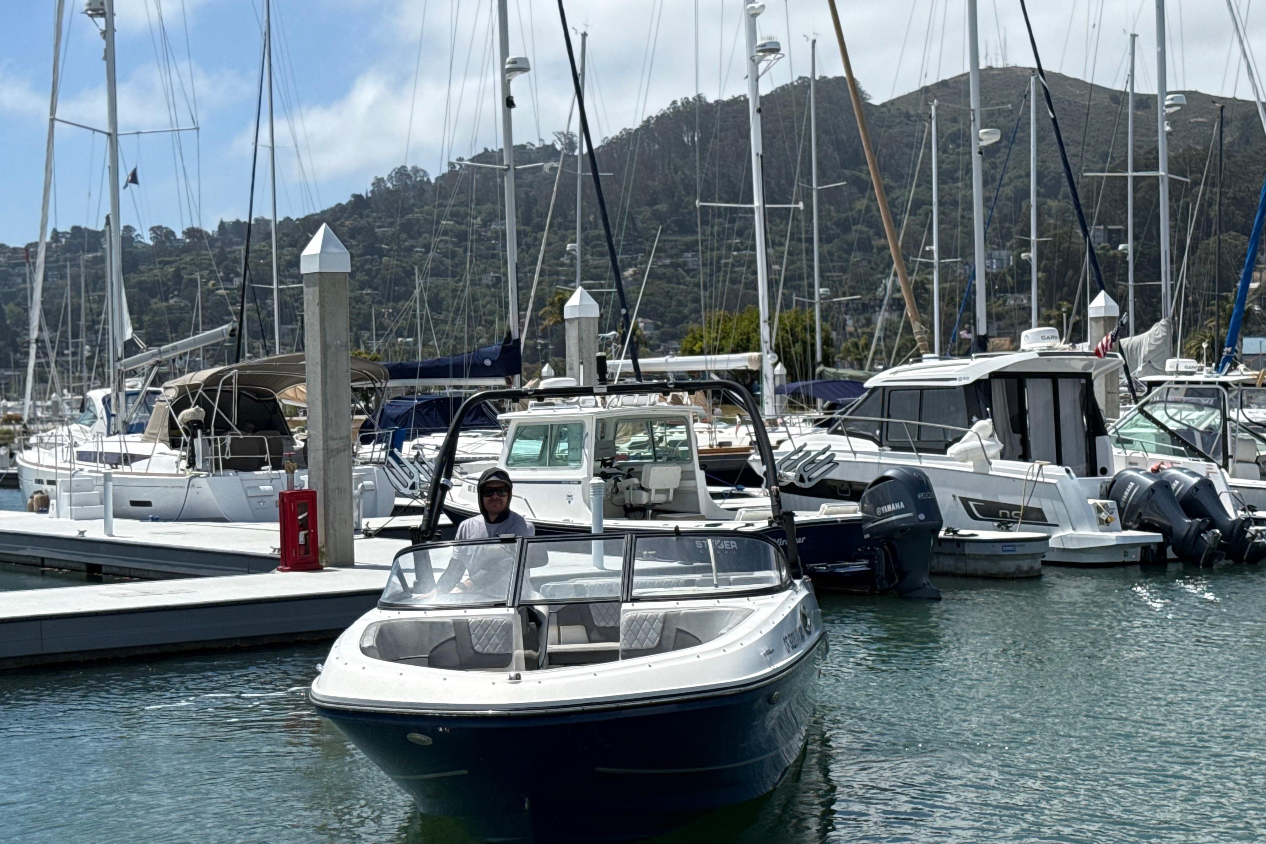 2021 Bayliner VR5 Bowrider I/O docked in a marina with sailboats and hills in the background.