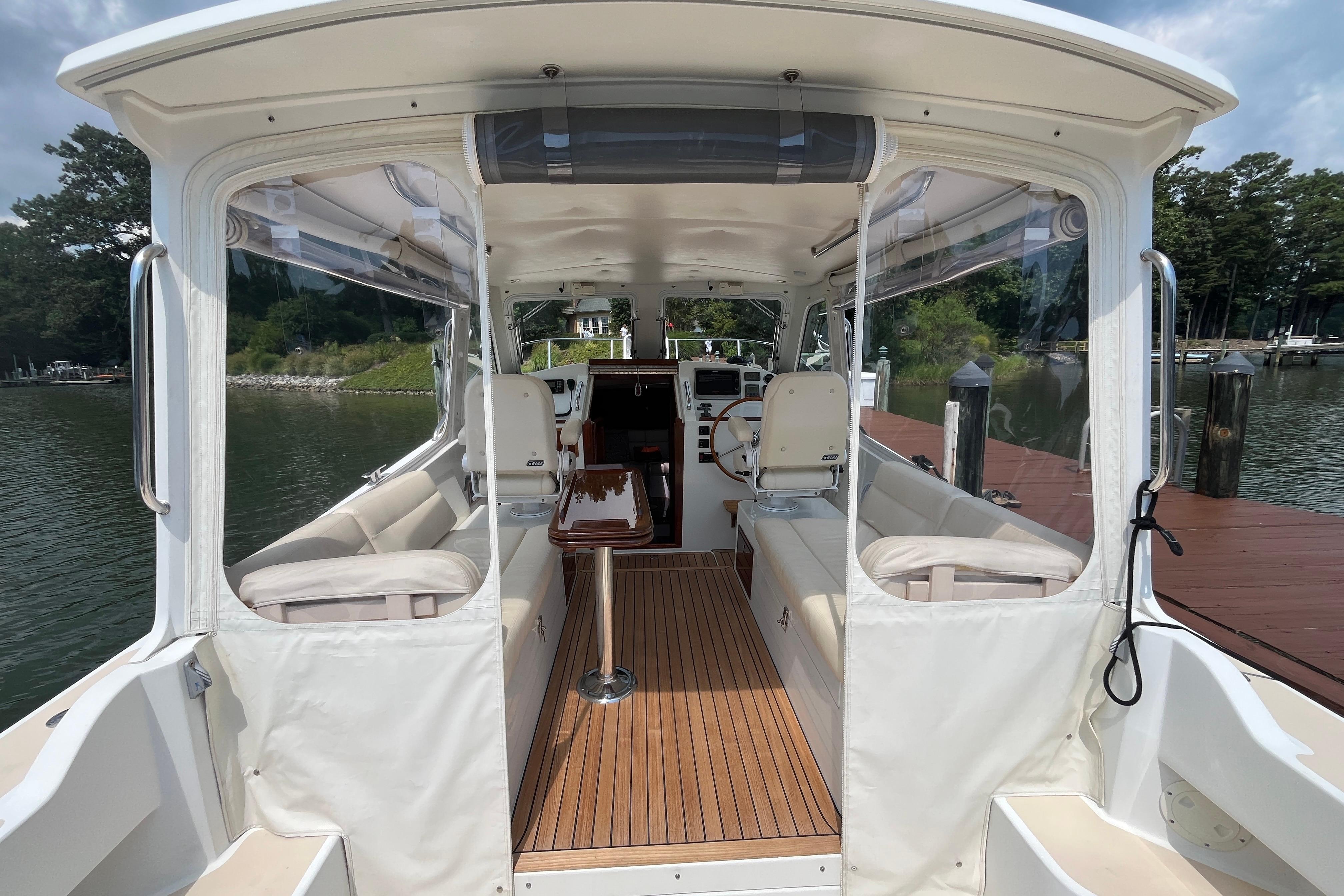 2006 MJM 34z boat interior with seating and helm, docked by a scenic waterfront.